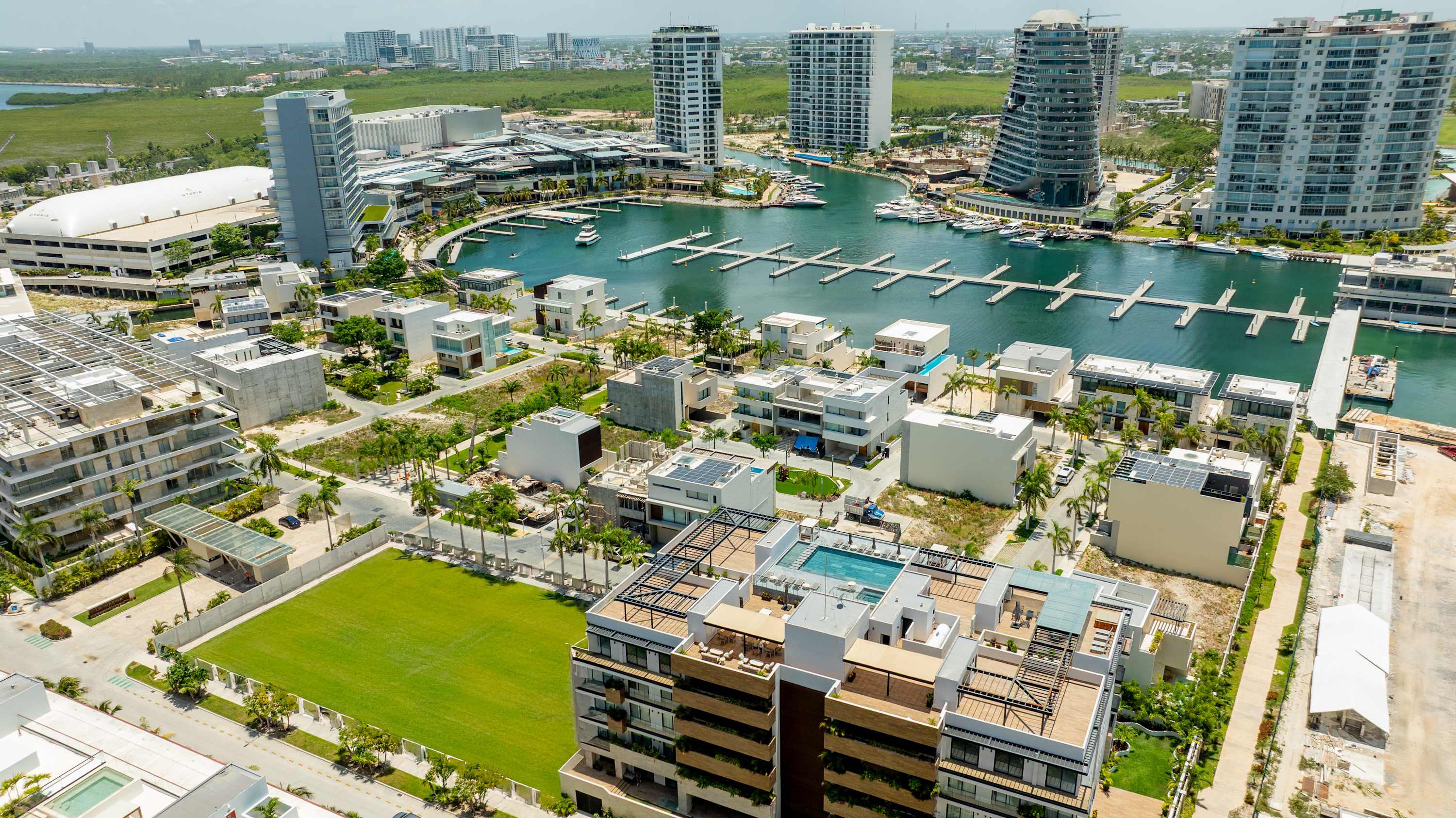 An aerial view of a modern waterfront development with sleek buildings and a marina.