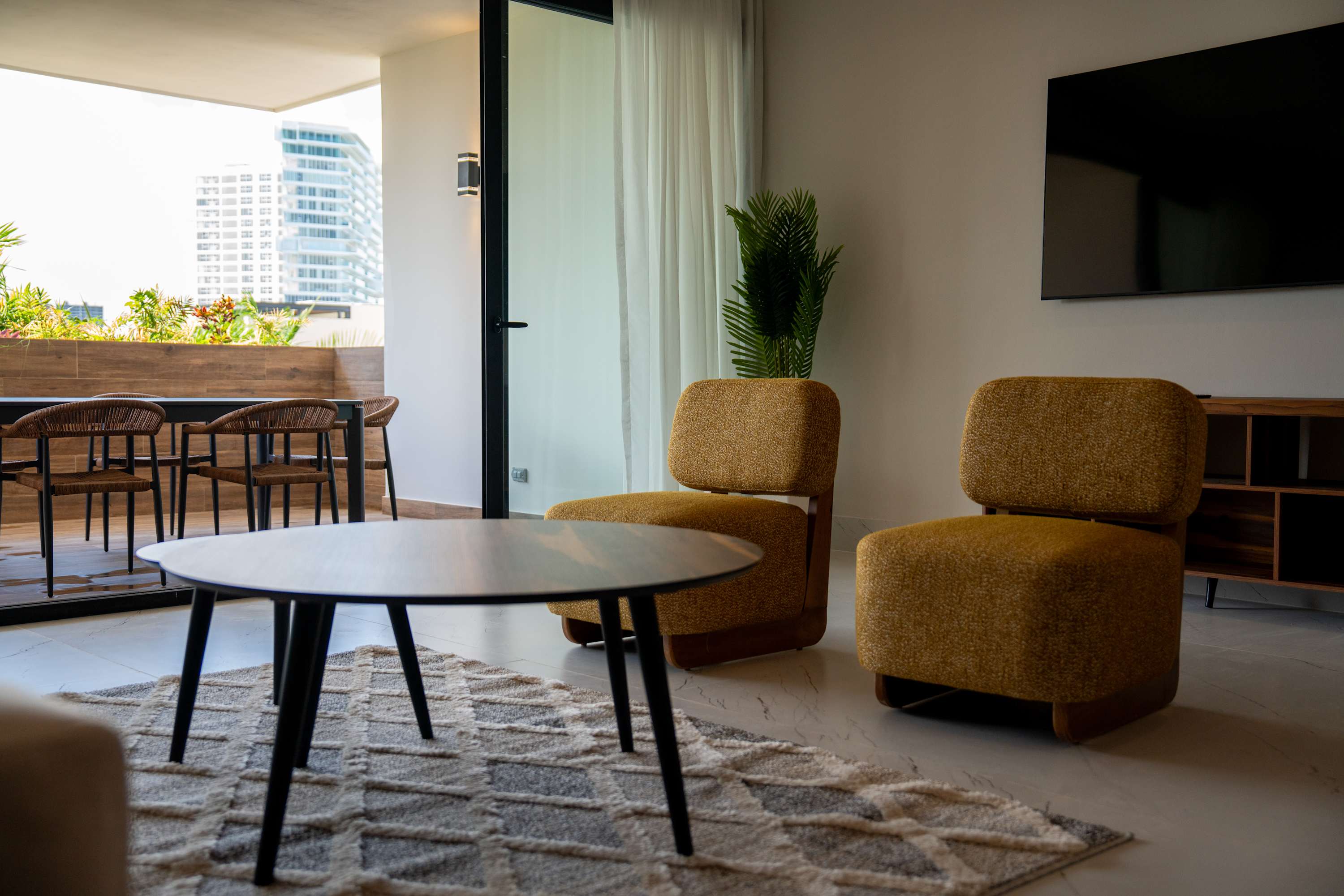 Modern living room with two yellow chairs, a coffee table, and a balcony view.