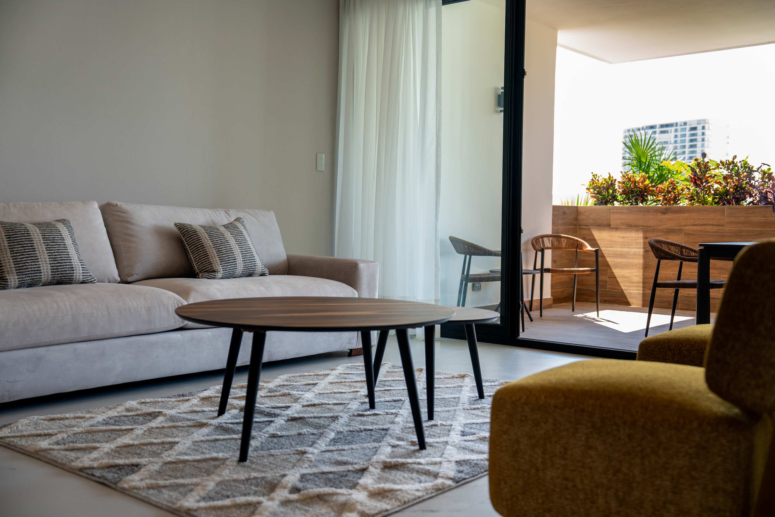 Sofa with patterned pillows, coffee table, and rug in a modern living room with a patio view.