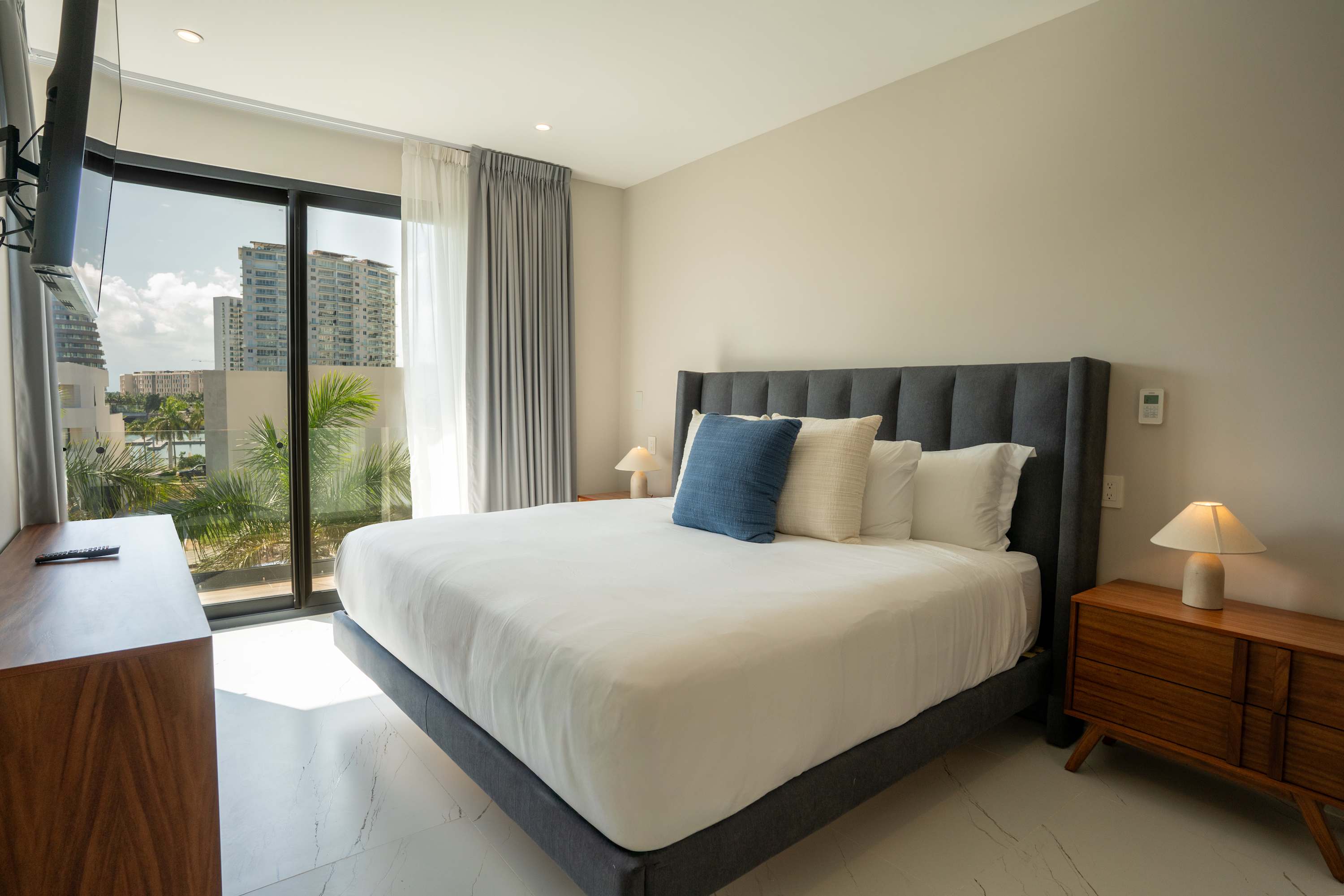 A king-size bed with gray headboard and white bedding.