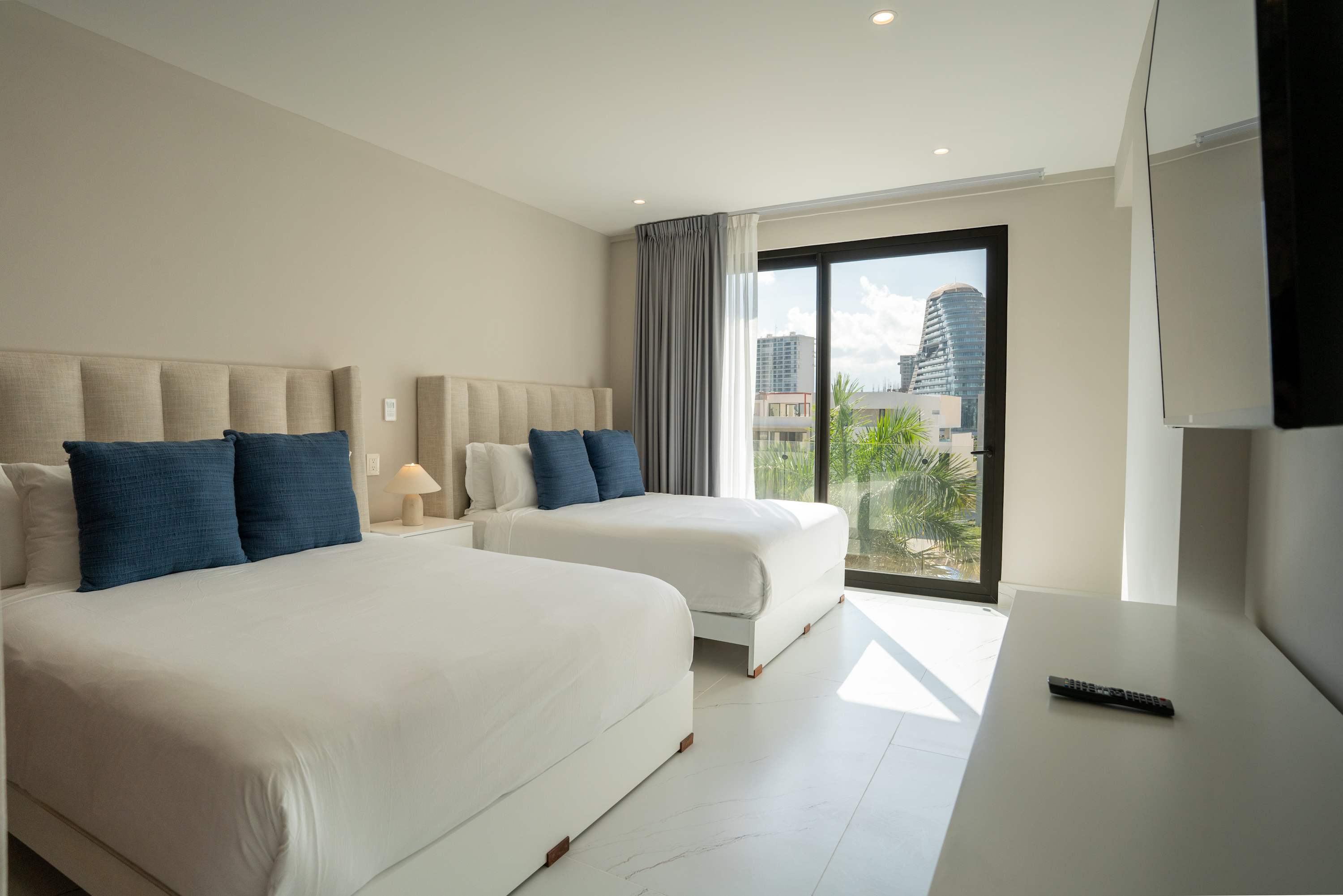 Two beds and a TV in a hotel room with a balcony view.