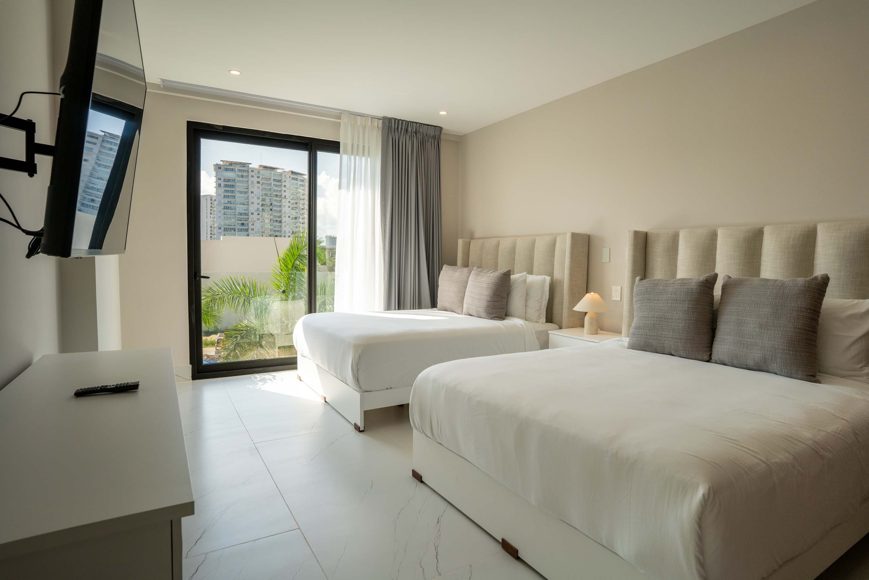 A bedroom with two queen beds, a TV, and a large window with a city view.