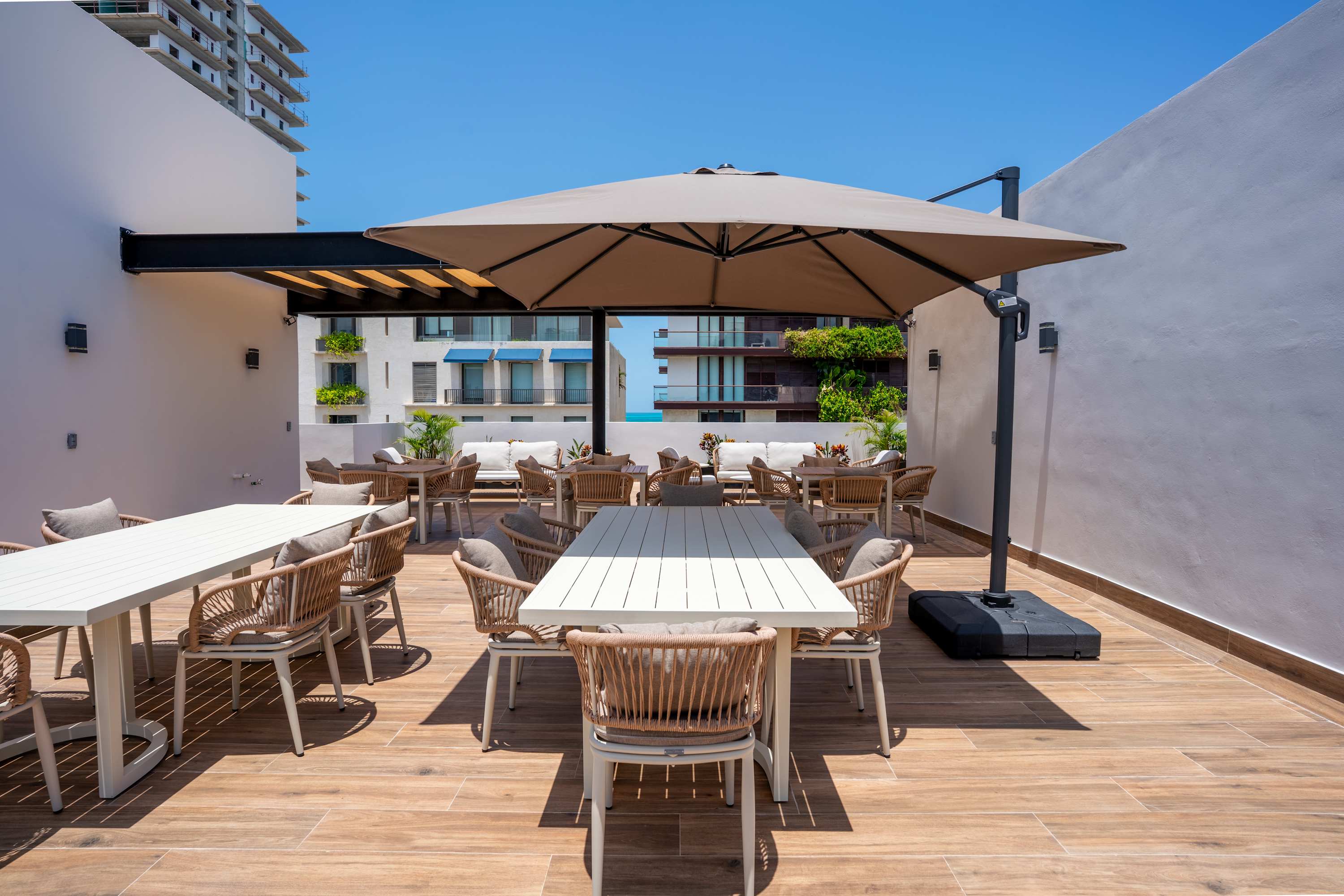 Rooftop terrace with tables, chairs, and an umbrella.