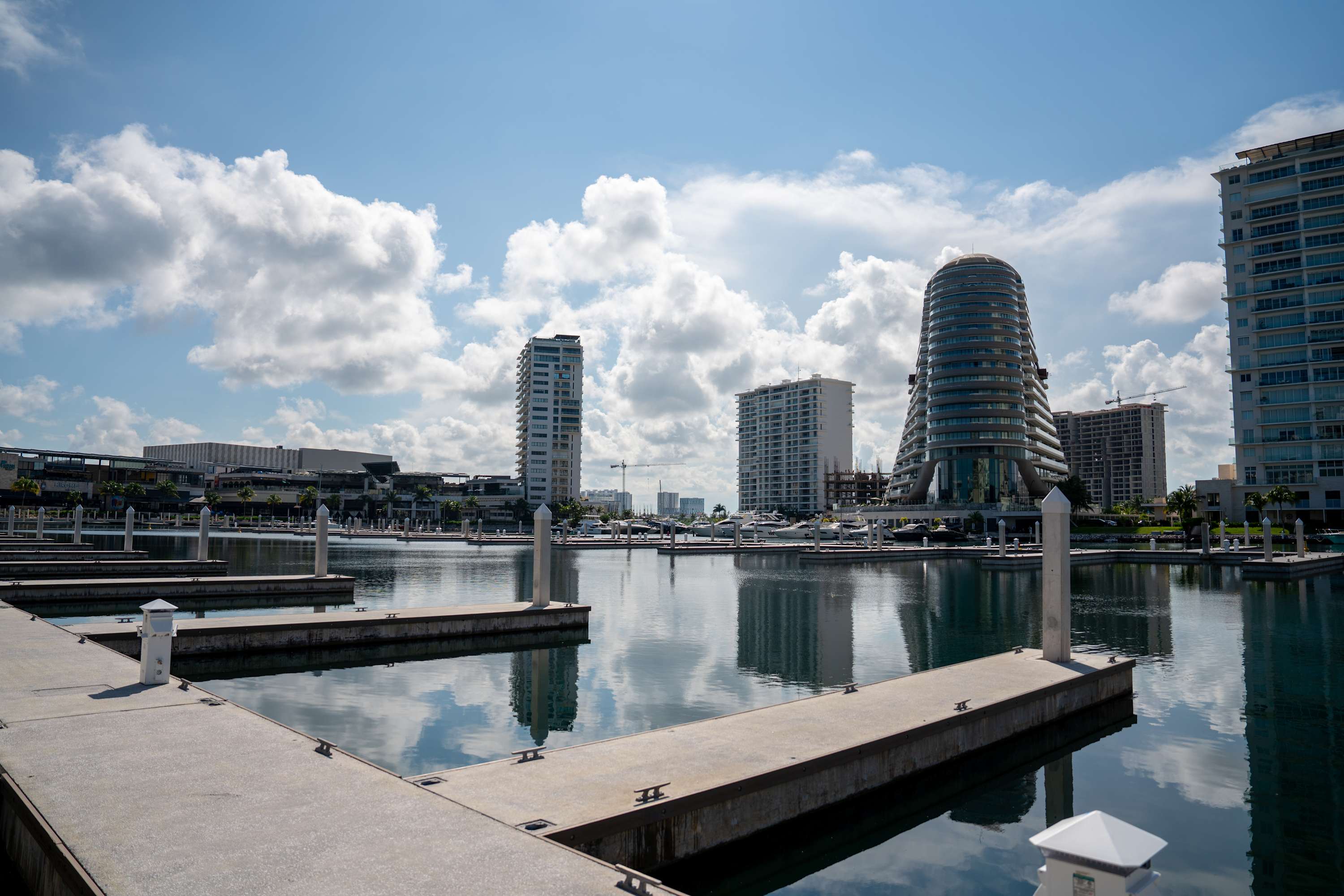 A marina with buildings and boats under a cloudy blue sky.