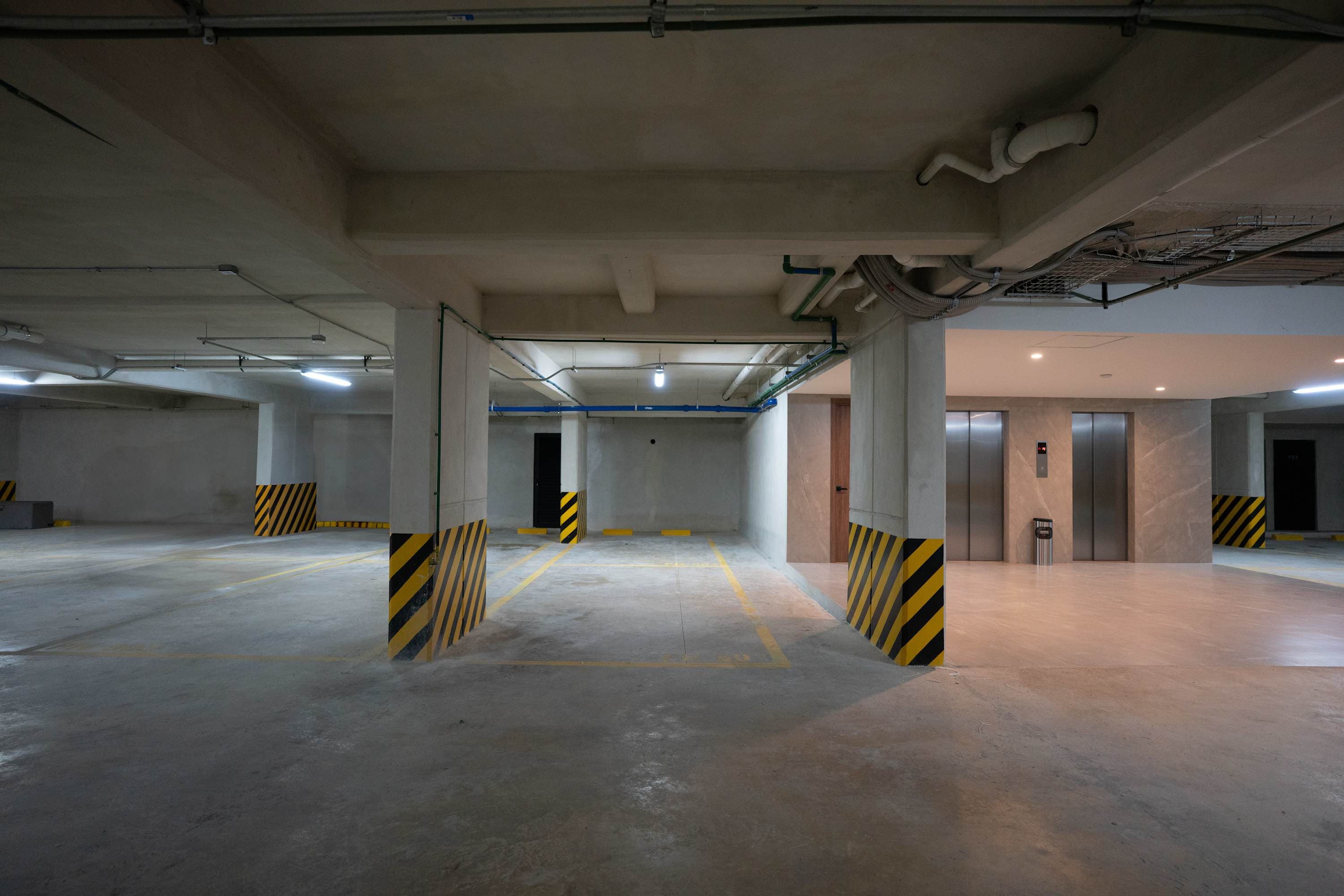 A well-lit concrete parking garage with yellow lines and hazard stripes on pillars.