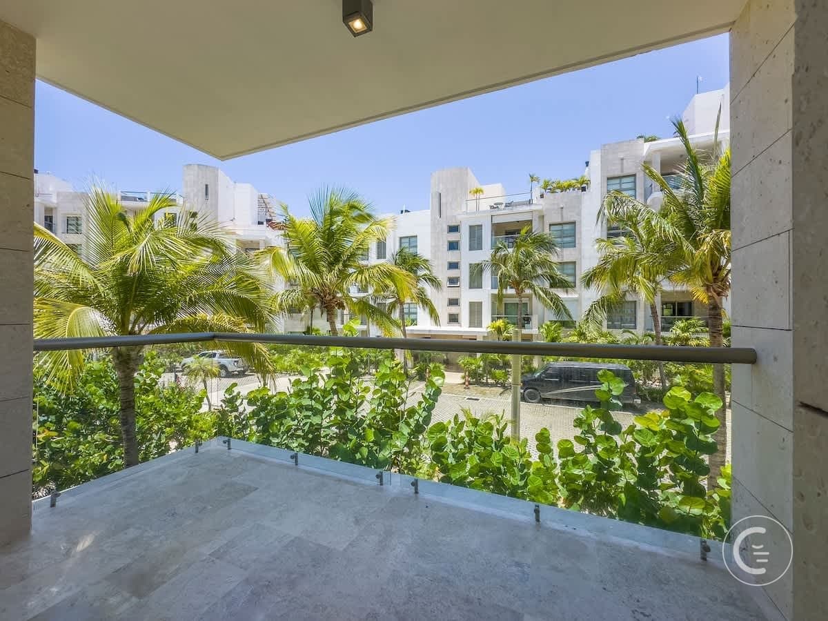 A balcony overlooks a street with palm trees and modern buildings.