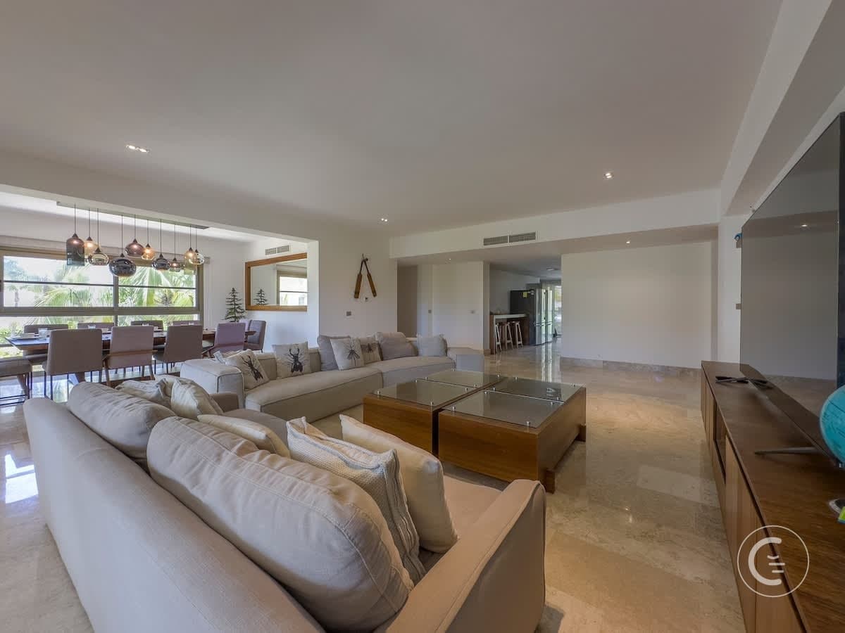 Large, open-plan living and dining room with a sectional sofa, coffee tables, and dining set.