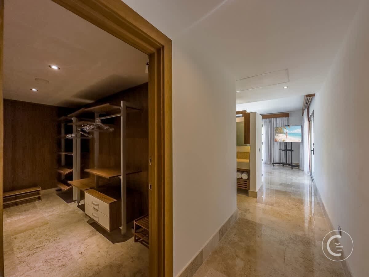 A hallway leads to a bedroom with a TV and a walk-in closet.