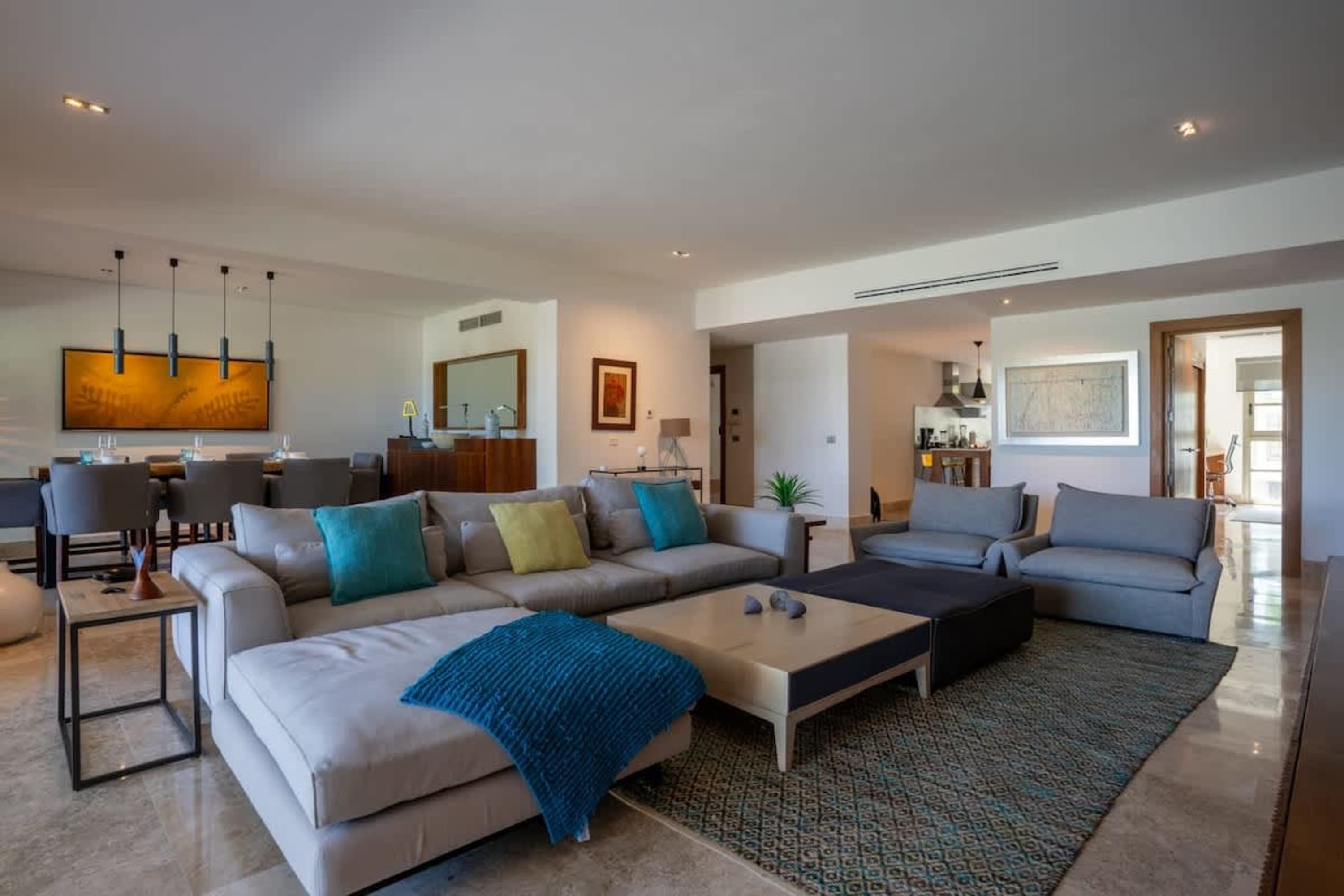 A spacious living room with a sectional sofa, coffee table, and two armchairs.