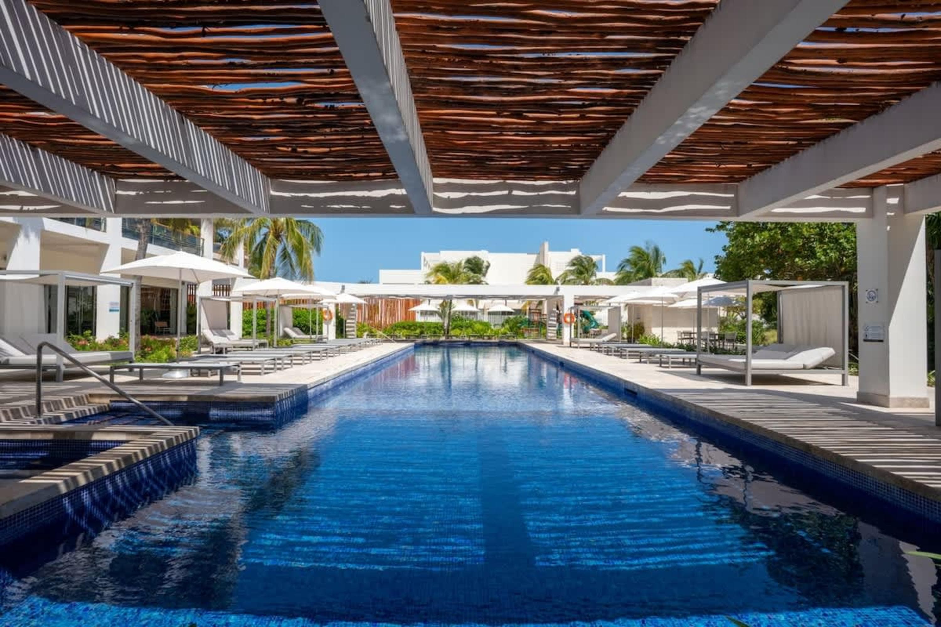 Luxurious resort pool with cabanas, lounge chairs, and palm trees.