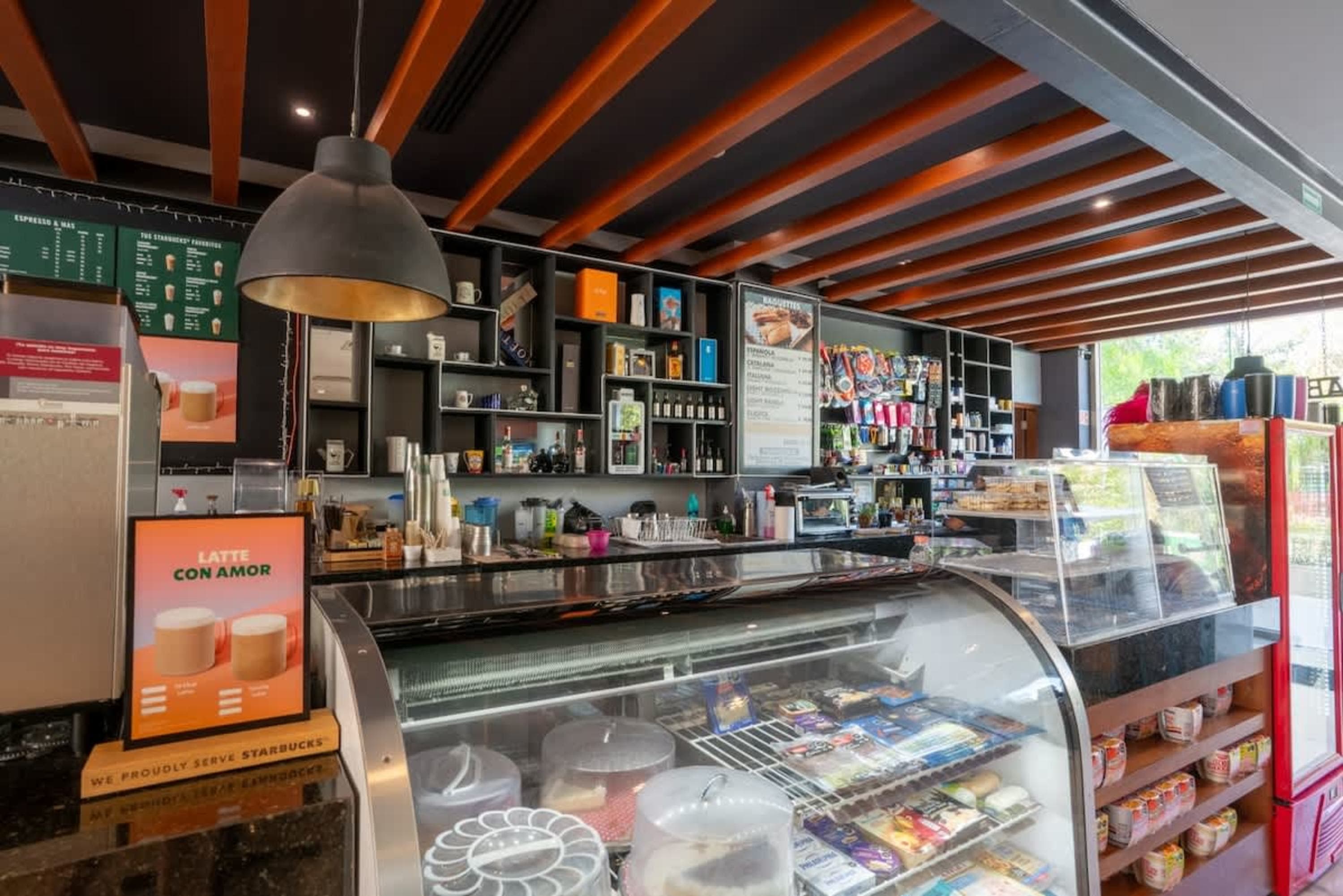A coffee shop counter with pastries, drinks, and shelves of merchandise.