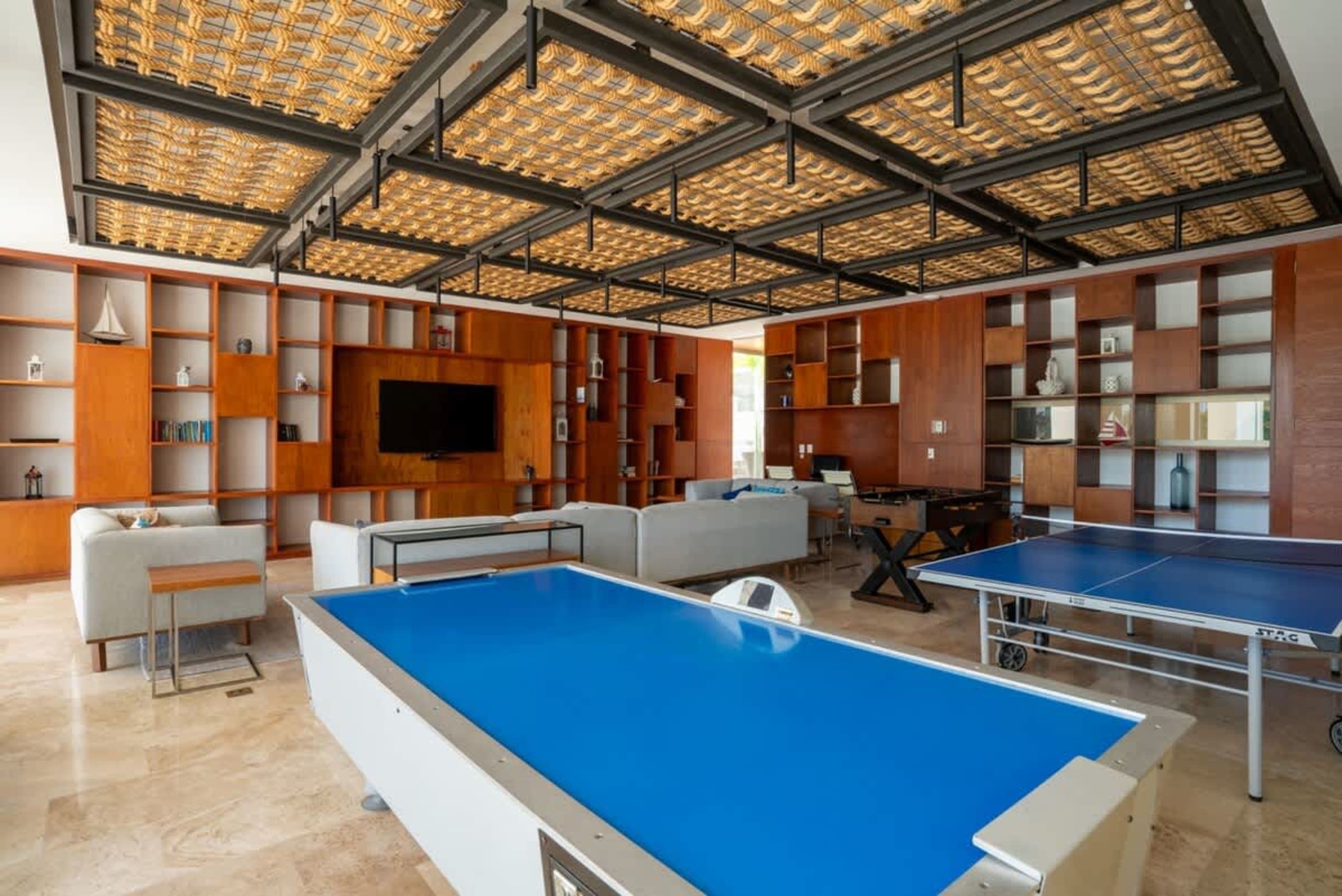 Room with pool table, ping pong table, foosball table, couches, and shelves.