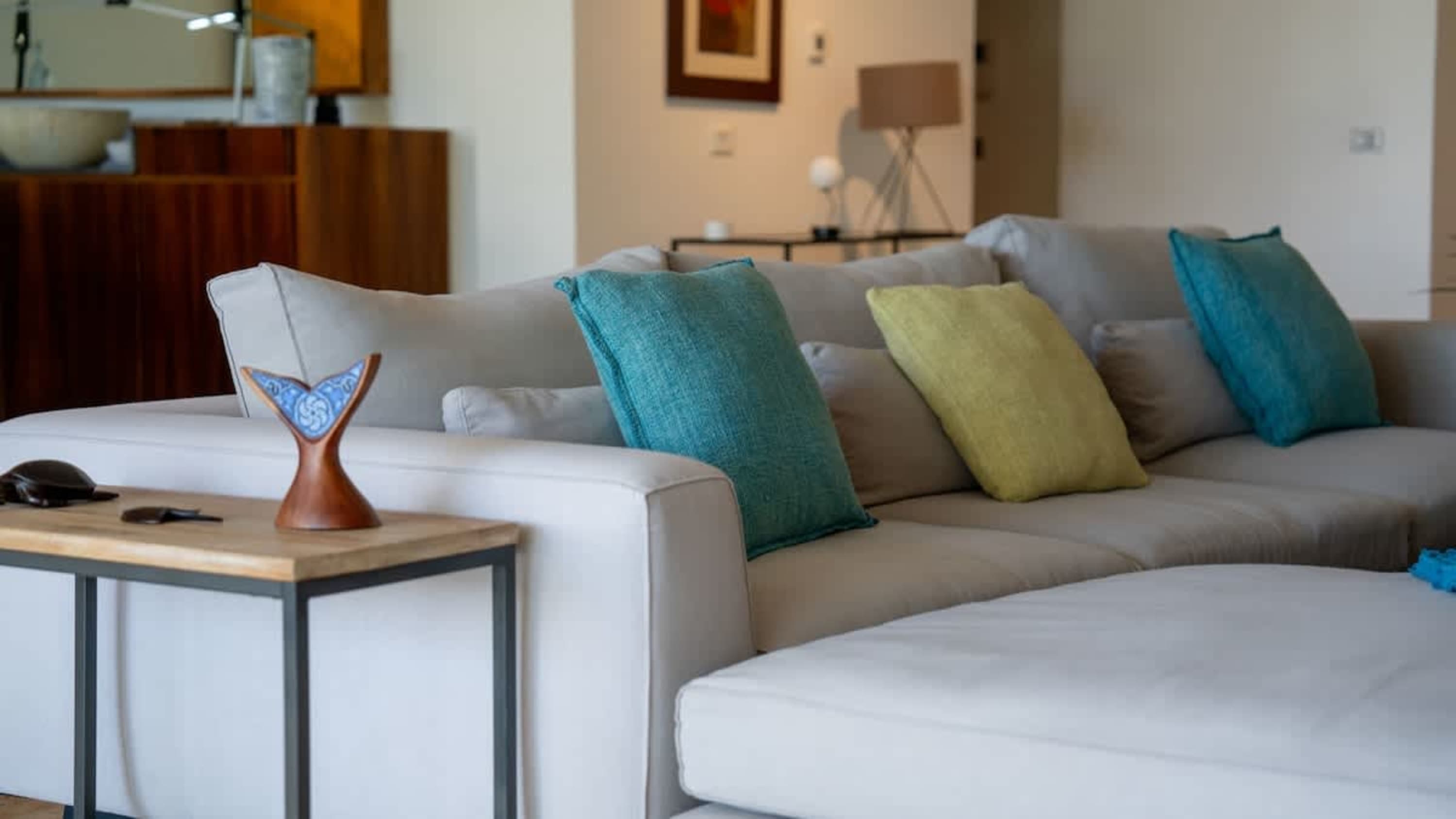 A light grey sectional sofa with teal and lime green throw pillows.