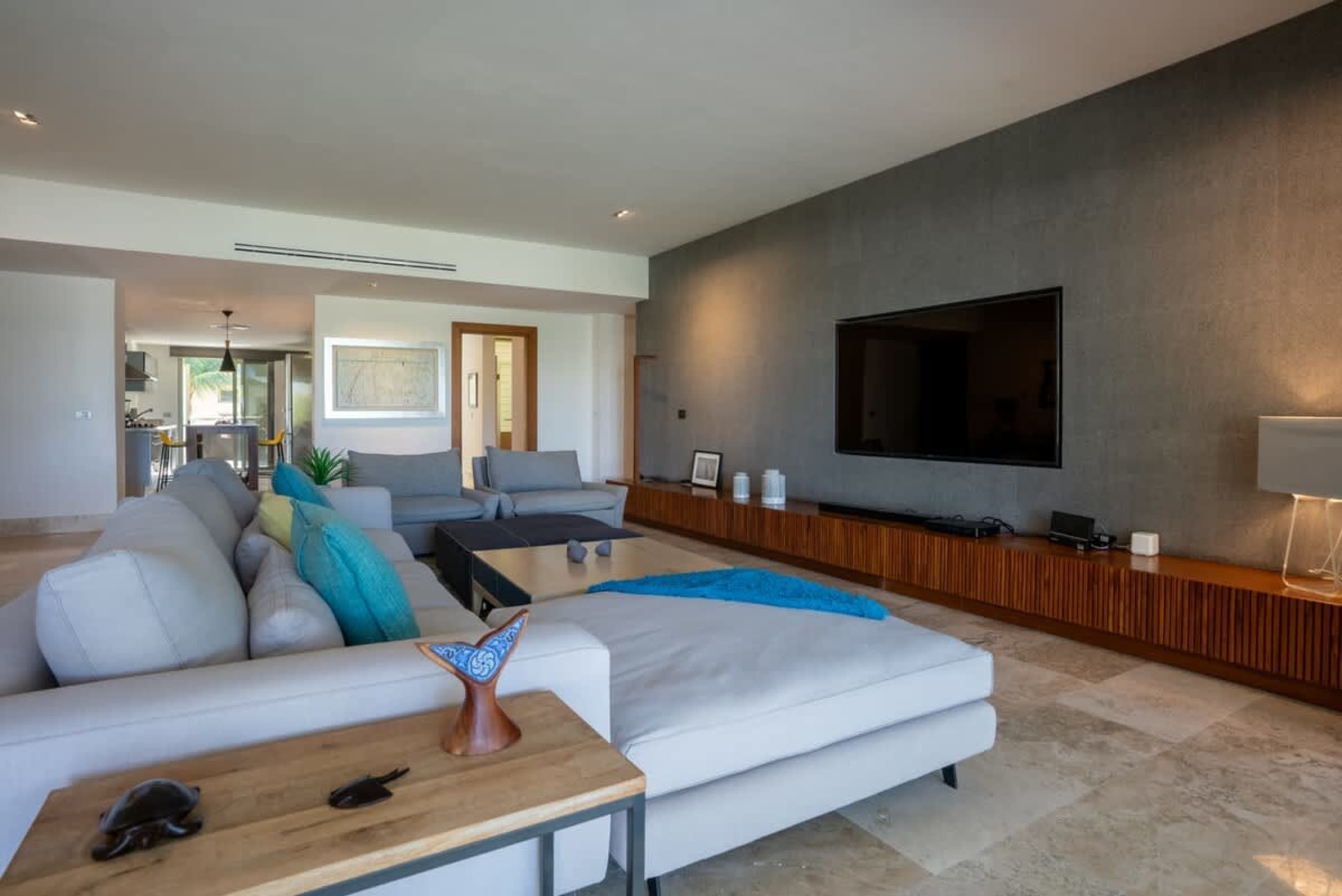 A modern living room with a large sectional sofa, a television, and a long wooden media console.
