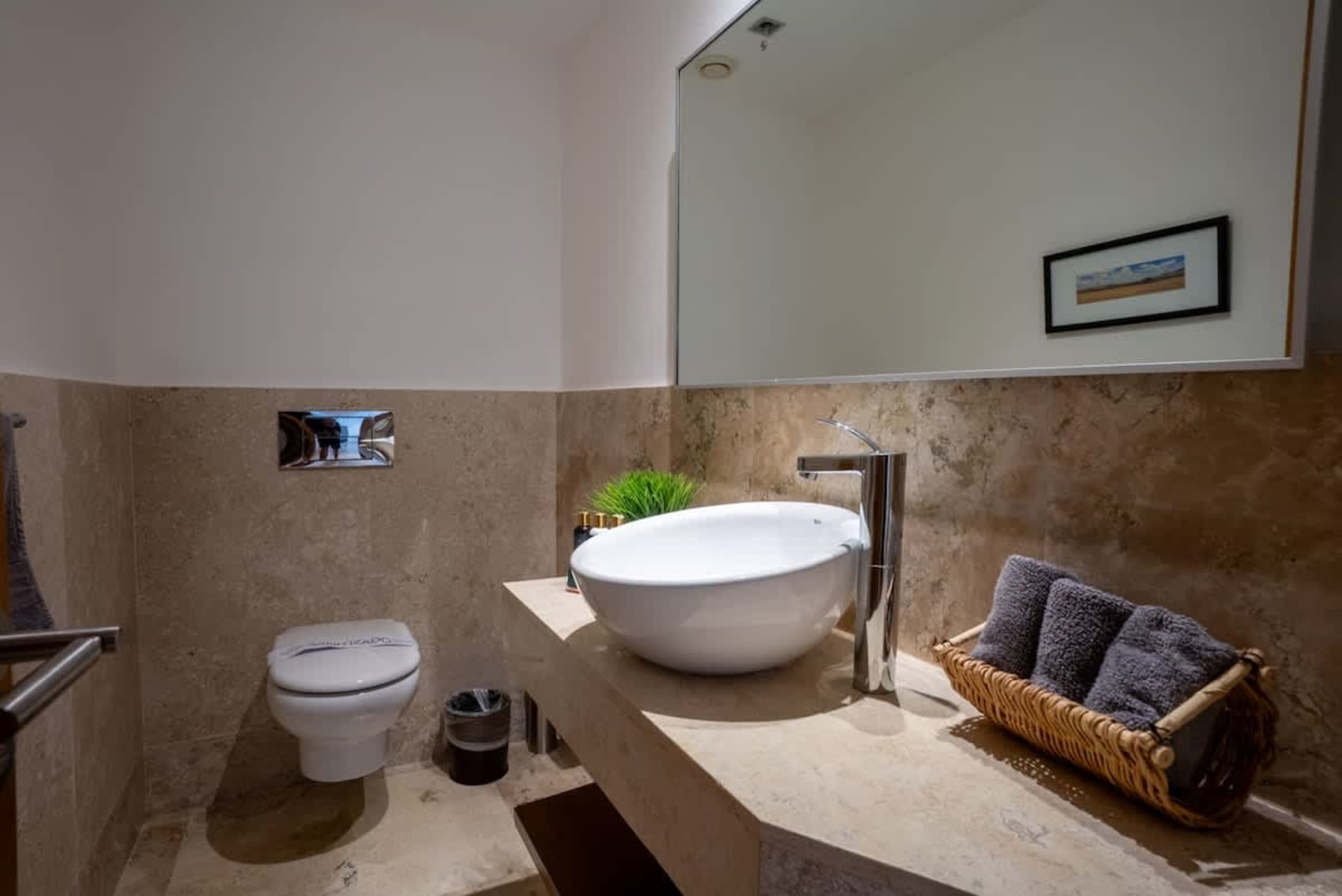 A modern bathroom with a toilet, sink, and mirror.