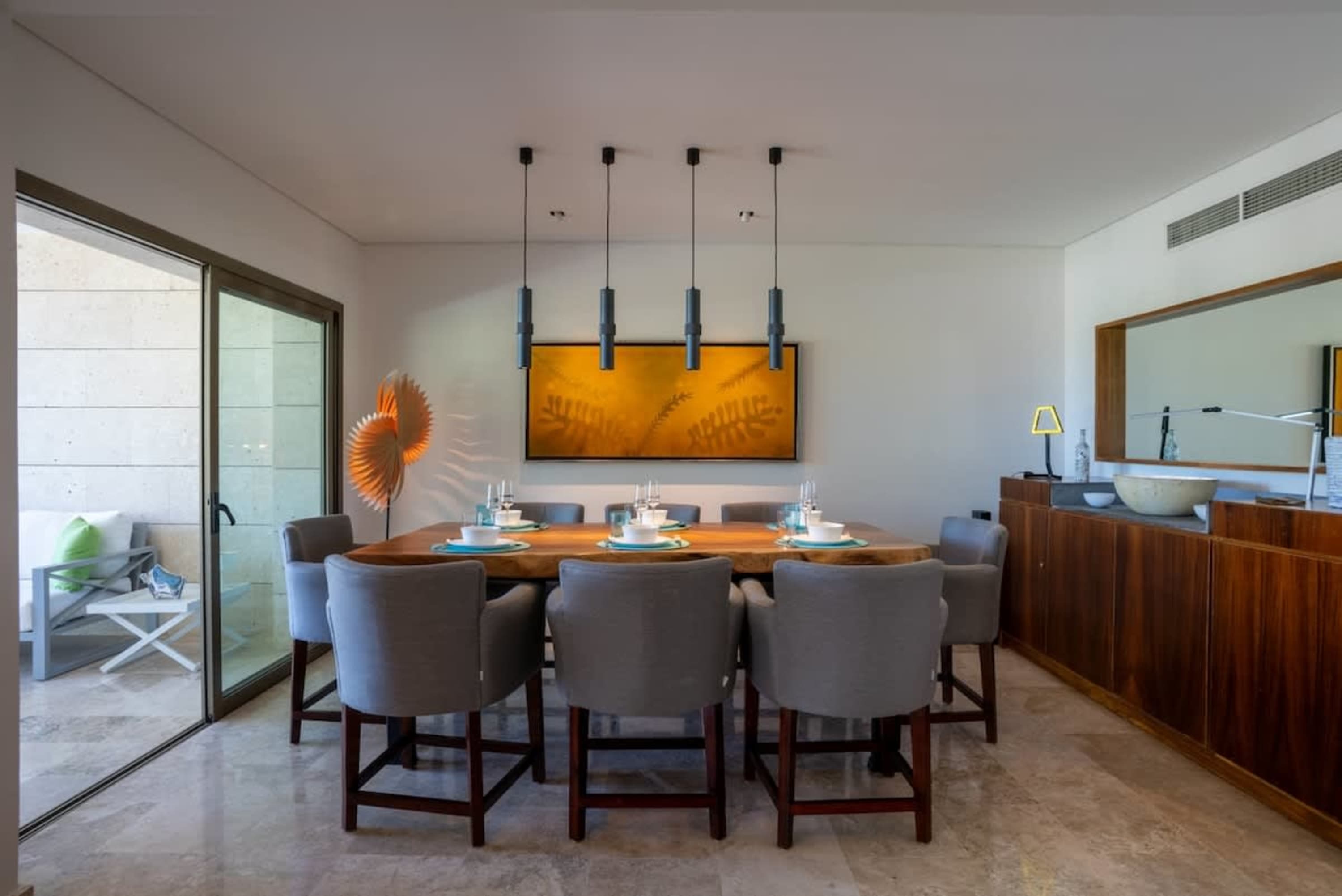 A modern dining room with a wooden table, gray chairs, and abstract art.