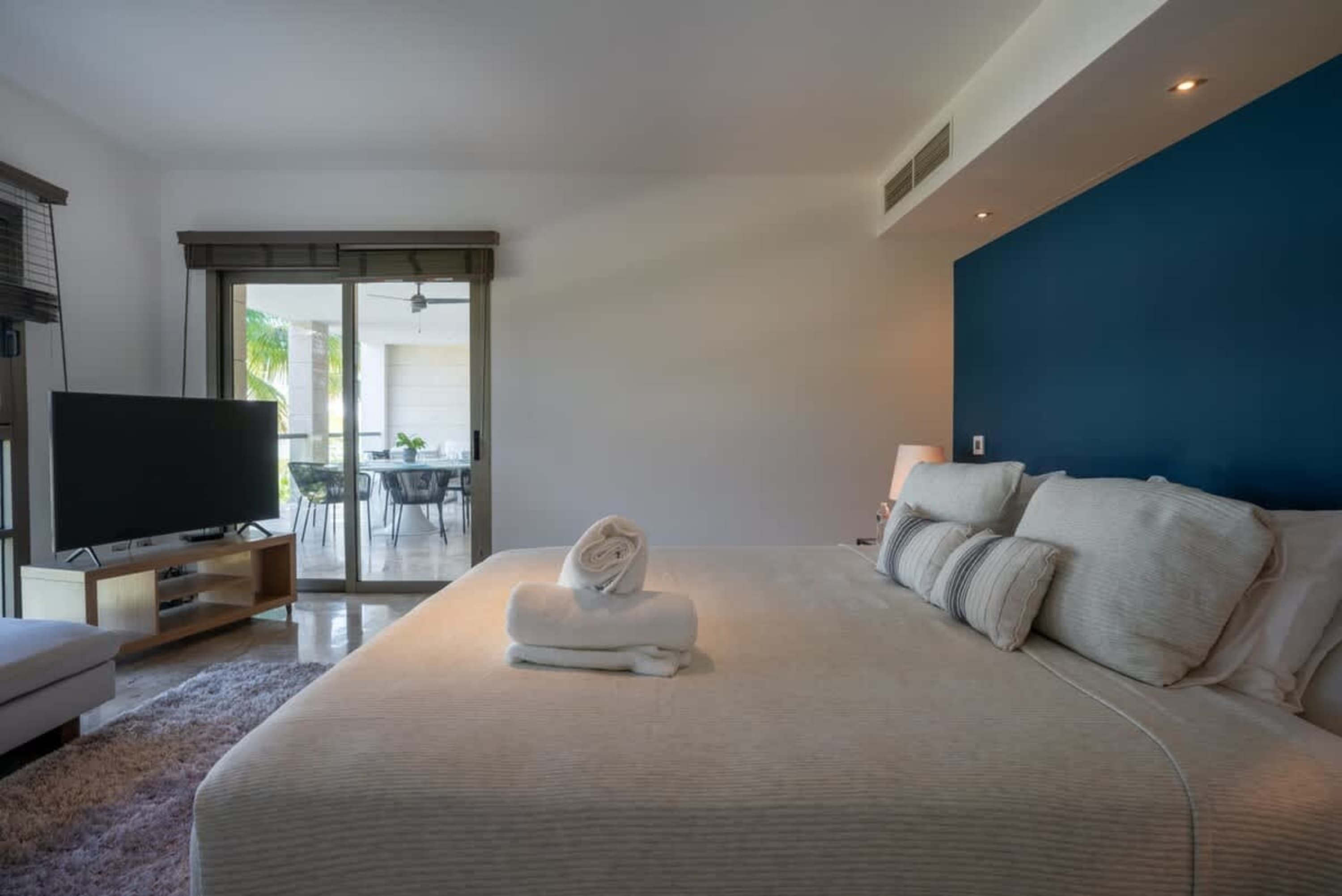 A bedroom with a large bed and blue accent wall.