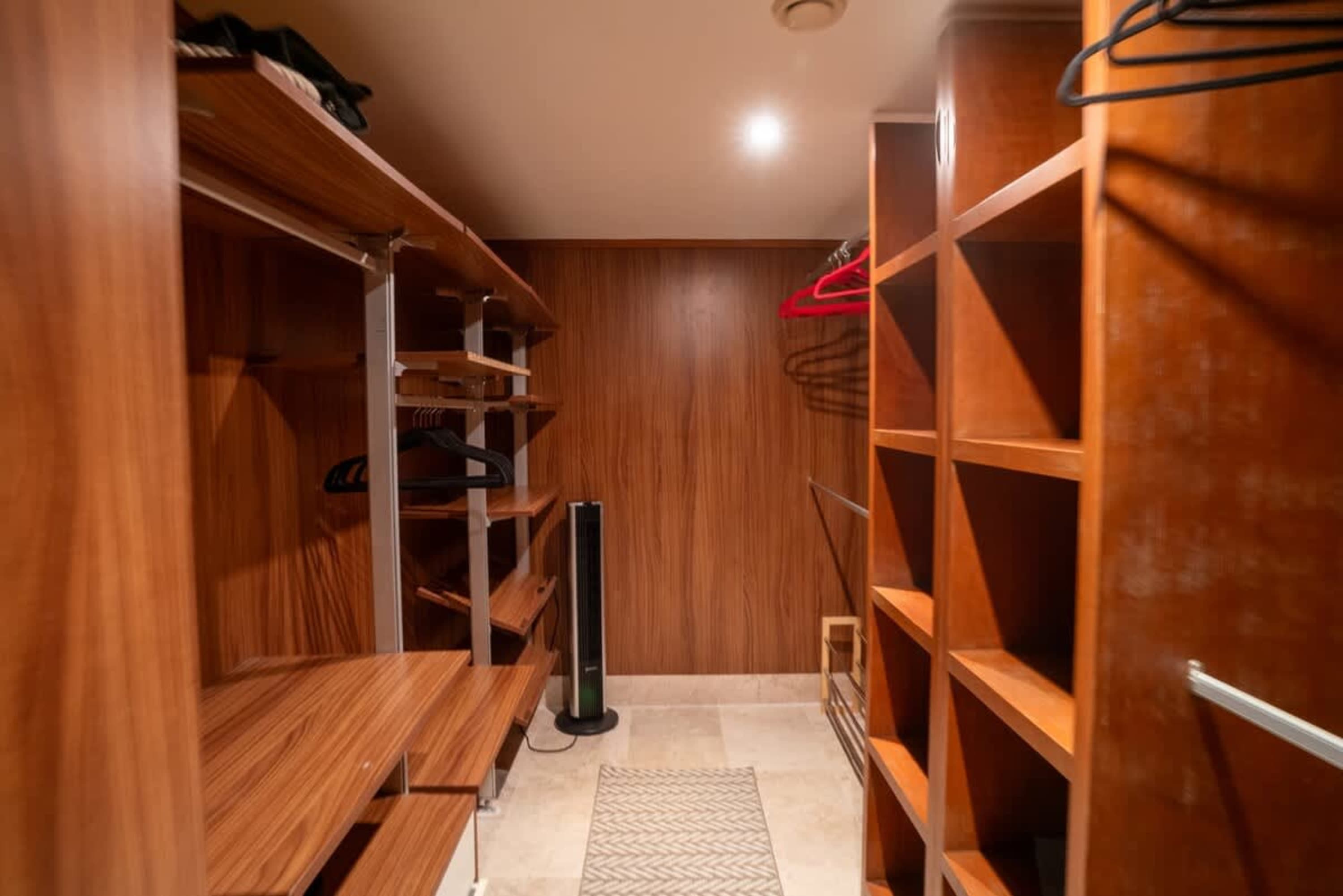 Walk-in closet with wooden shelves and hanging rods.