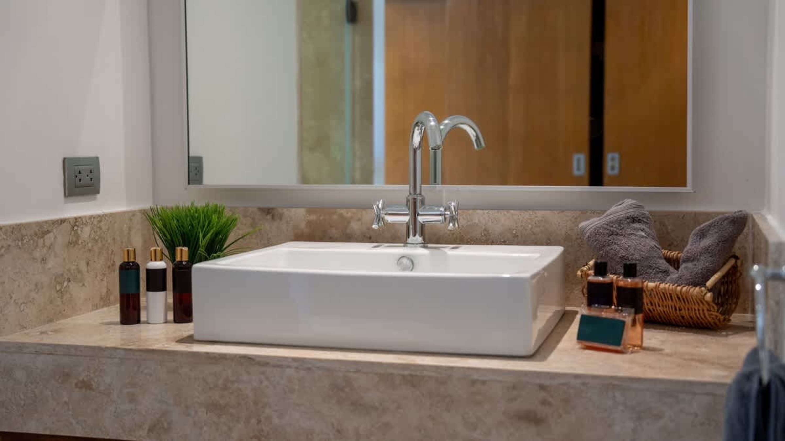 A bathroom vanity with a white sink, chrome faucet, and marble countertop.