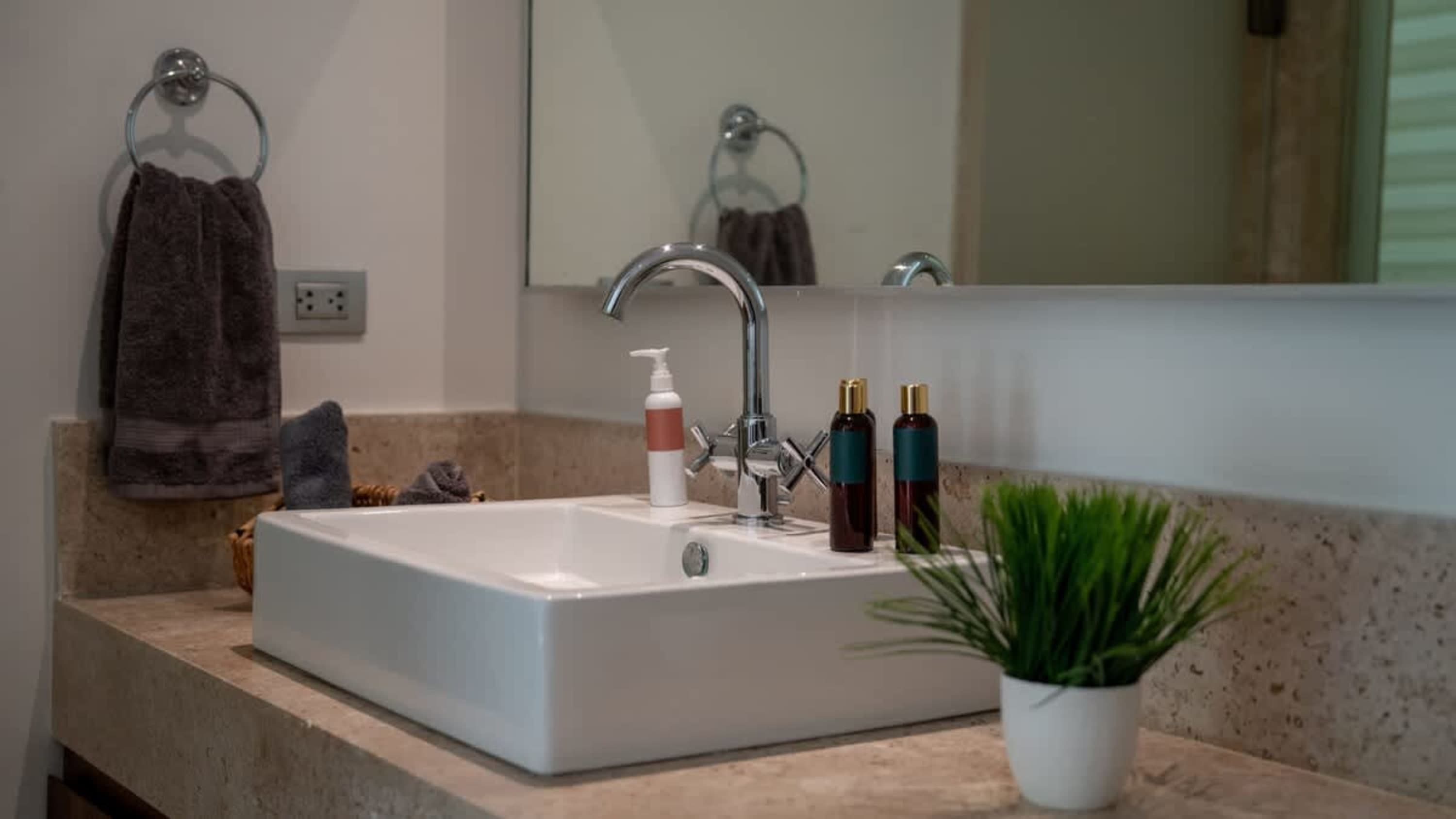 A bathroom sink with a chrome faucet, soap dispenser, and two bottles of product.