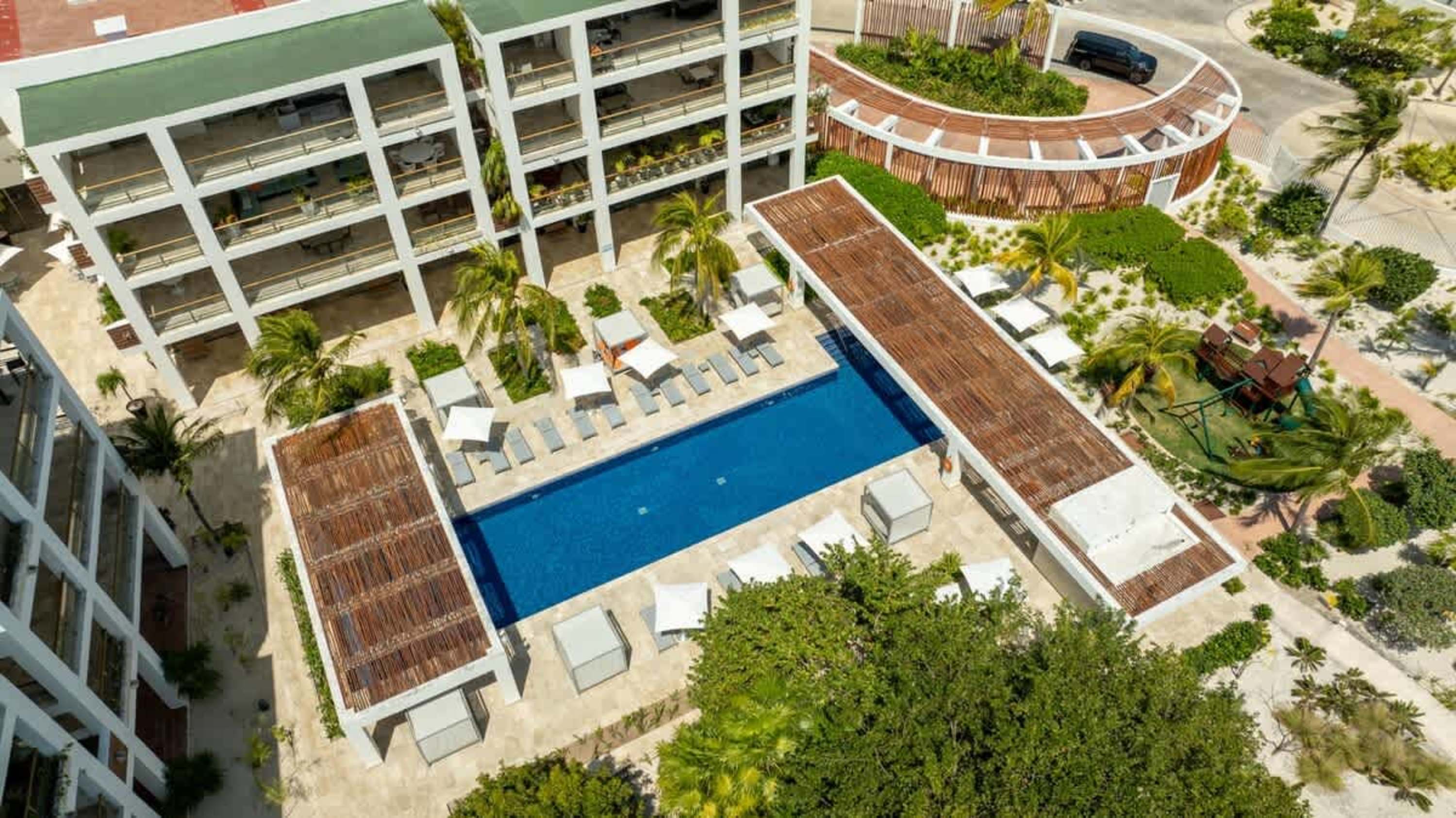 Aerial view of a modern resort complex with a swimming pool and lounge chairs.