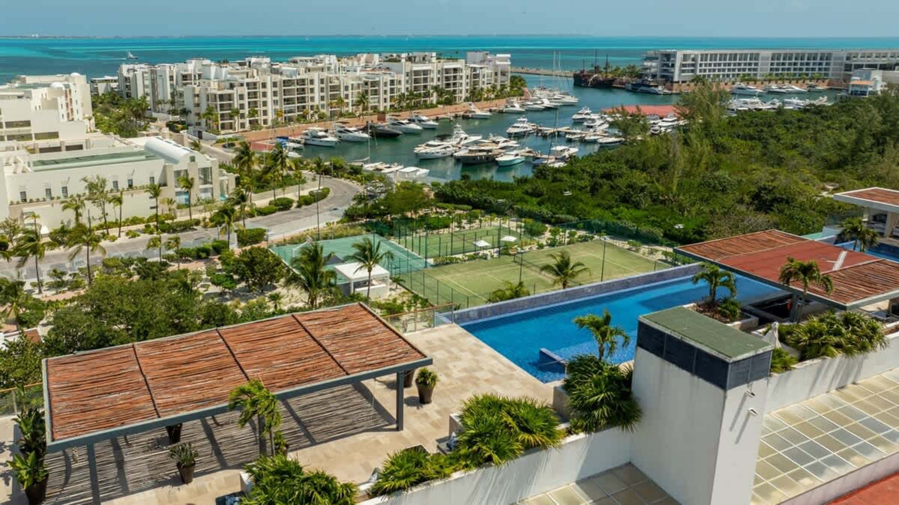 Aerial view of resort complex with marina, pool, and tennis courts.
