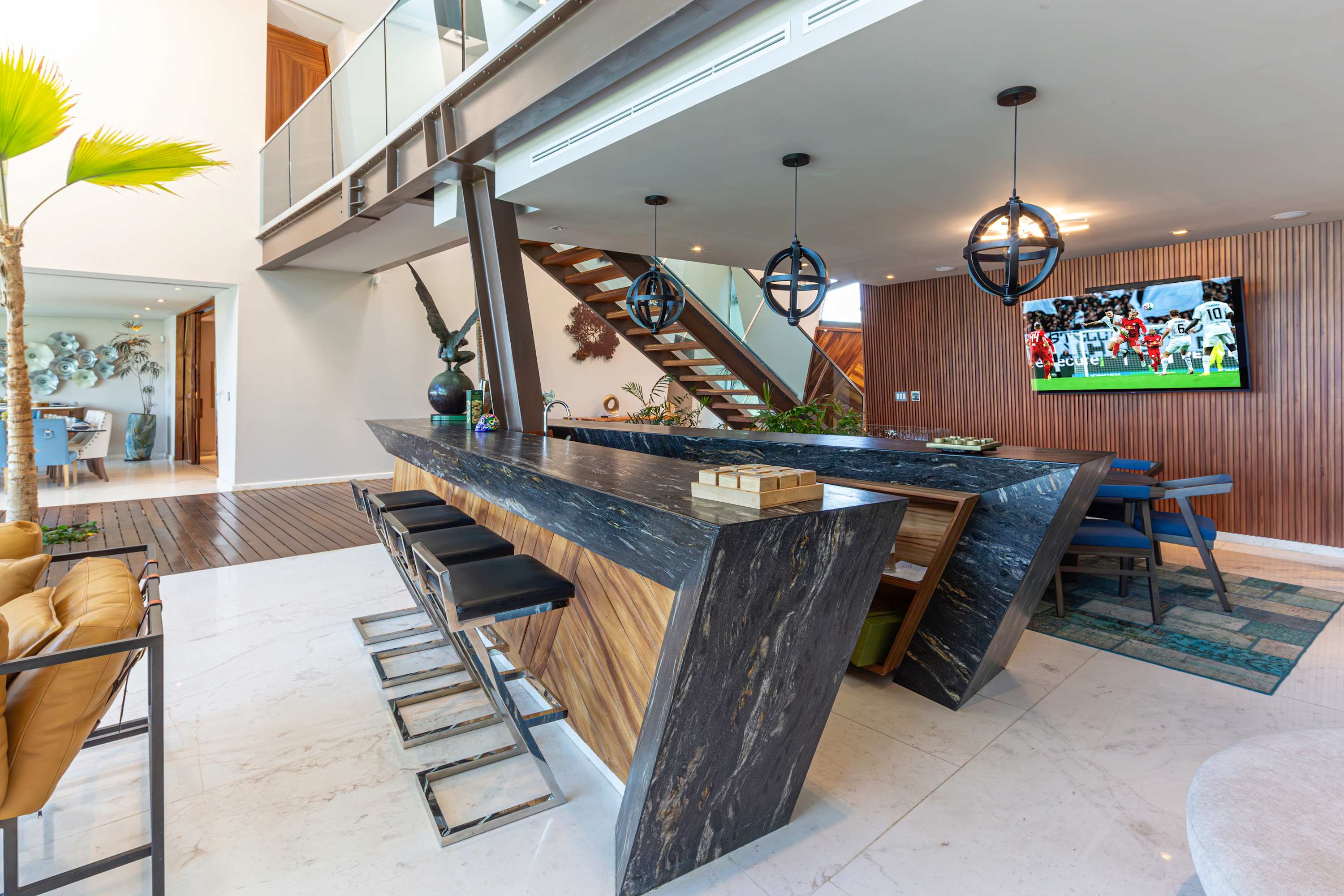 Sleek modern bar with marble countertop, wood accents, and bar stools, overlooking a living area wit