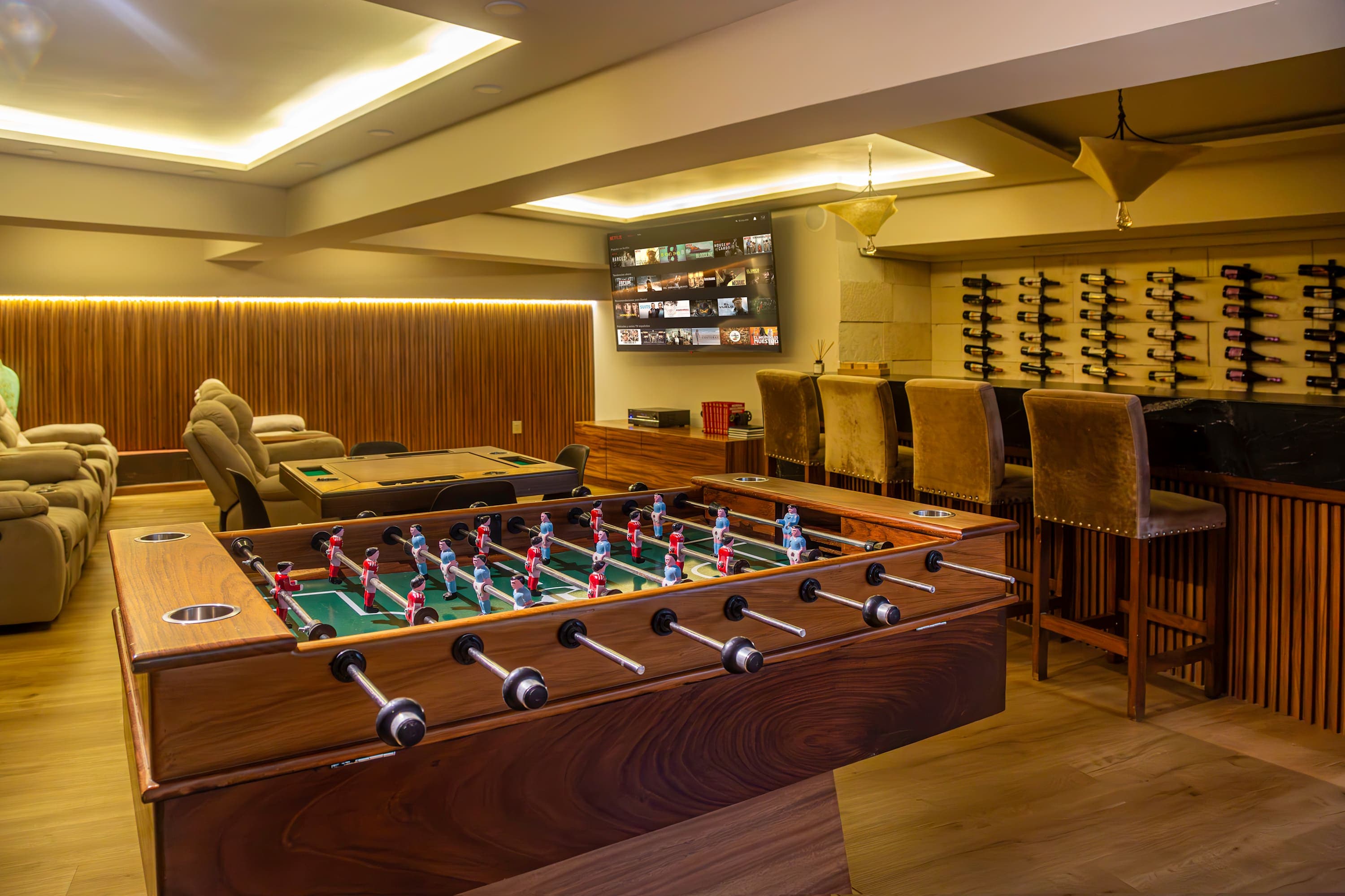 A foosball table and wine racks are in a room with comfortable seating and a bar.