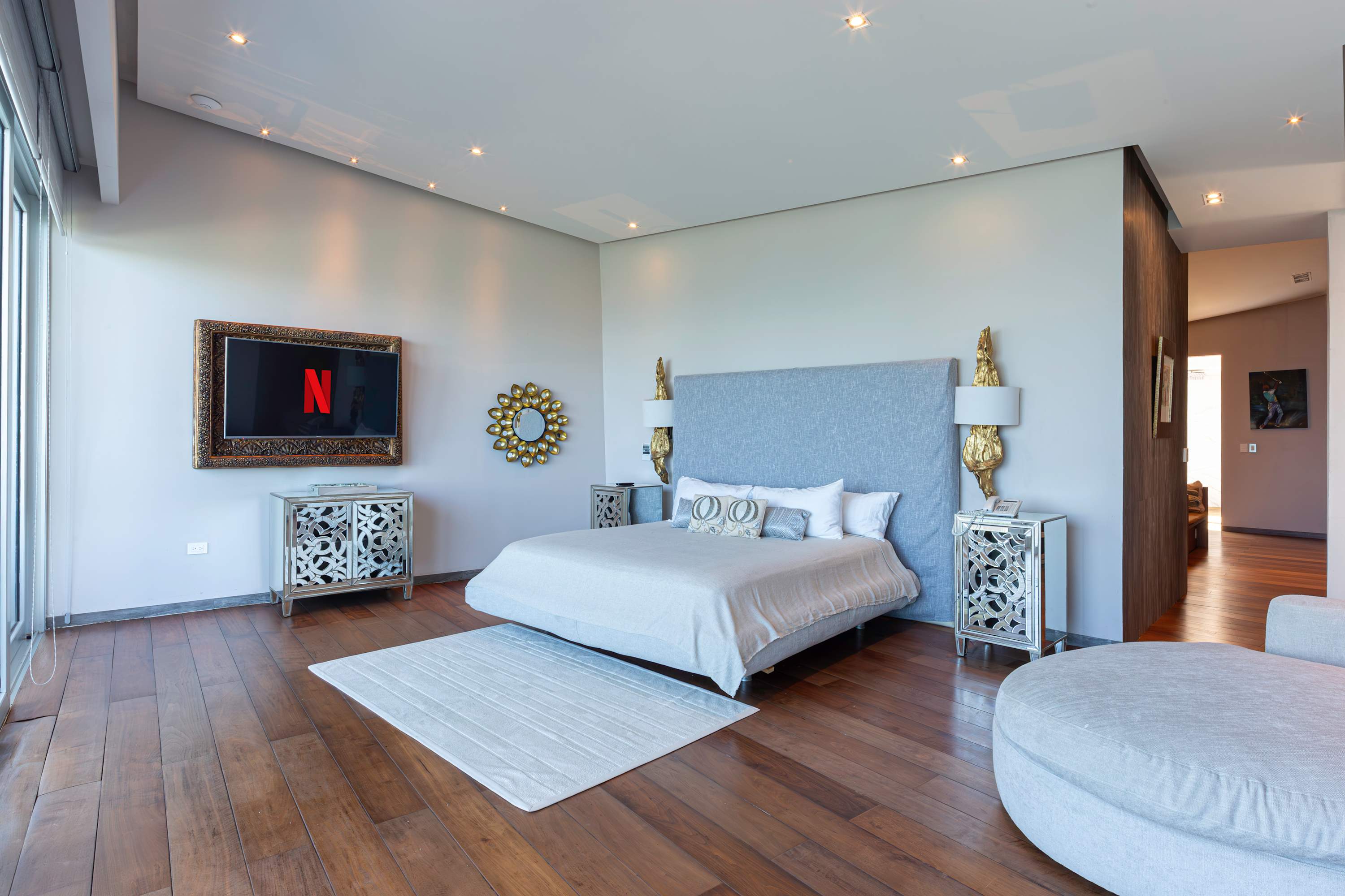 A contemporary bedroom with a king-size bed, a TV, and mirrored nightstands.