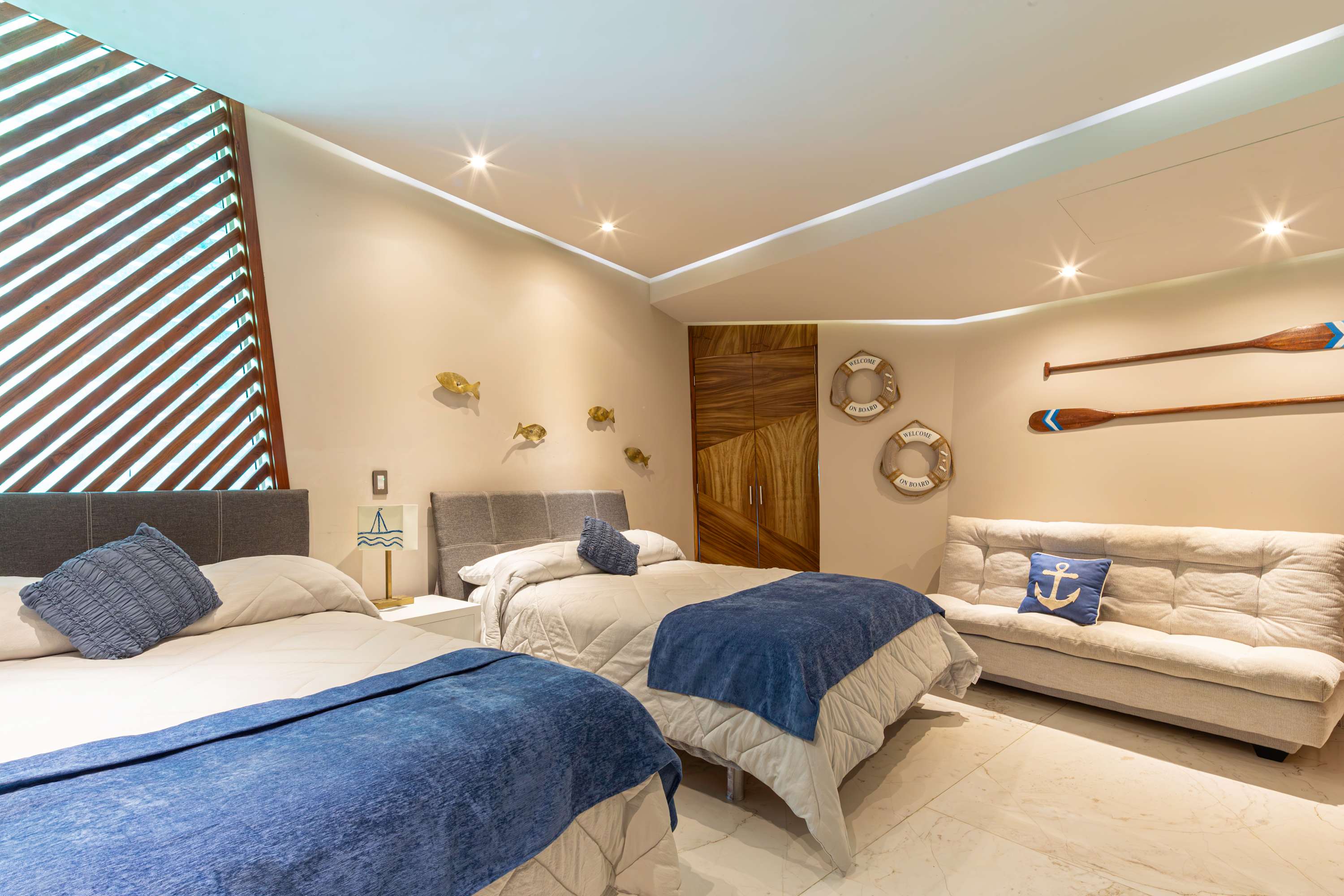 A bedroom with two beds, a couch, and nautical decor.