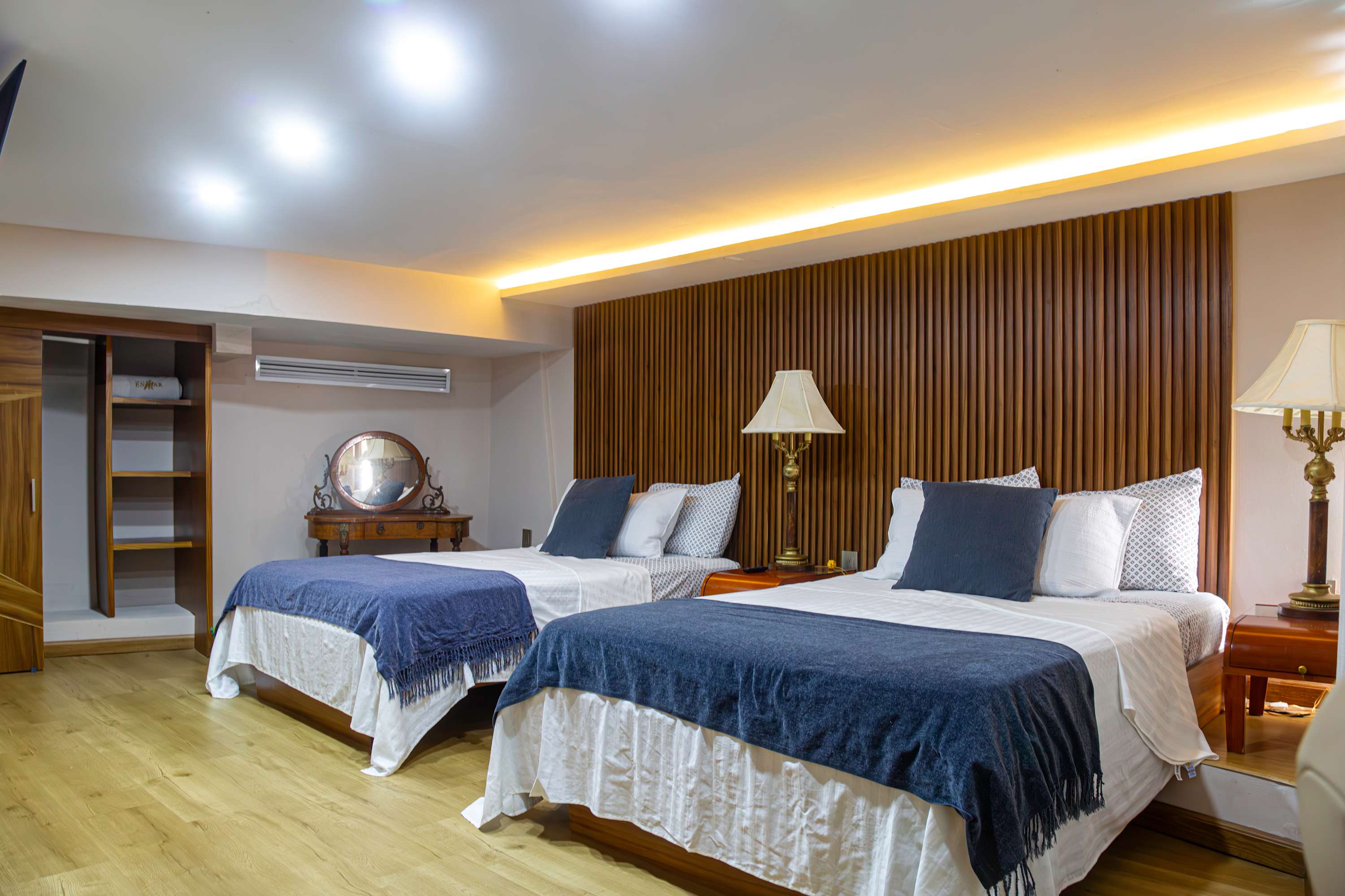 A well-lit bedroom with two beds, a wardrobe, and wooden accents.