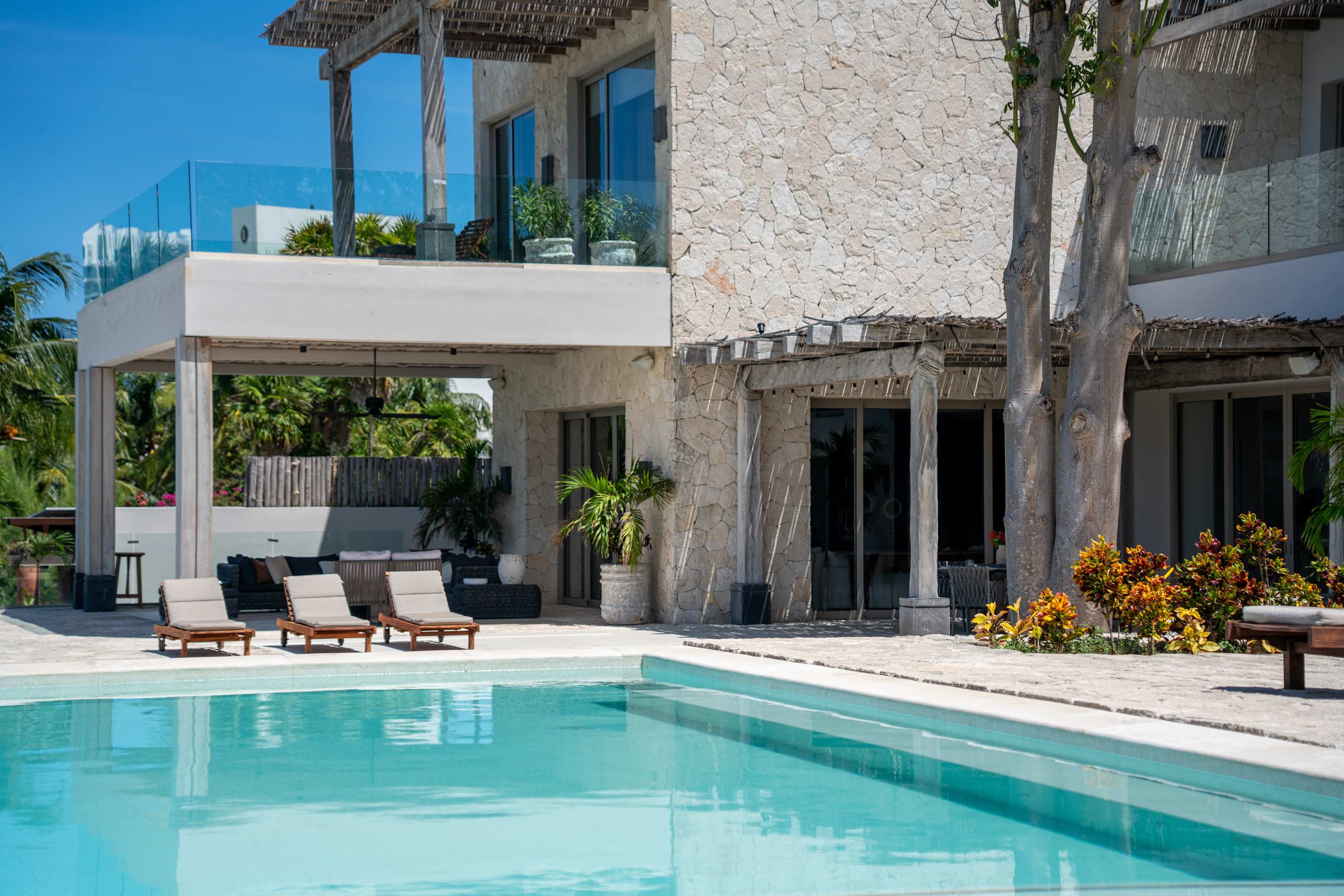 Modern stone house with a pool and lounge chairs.