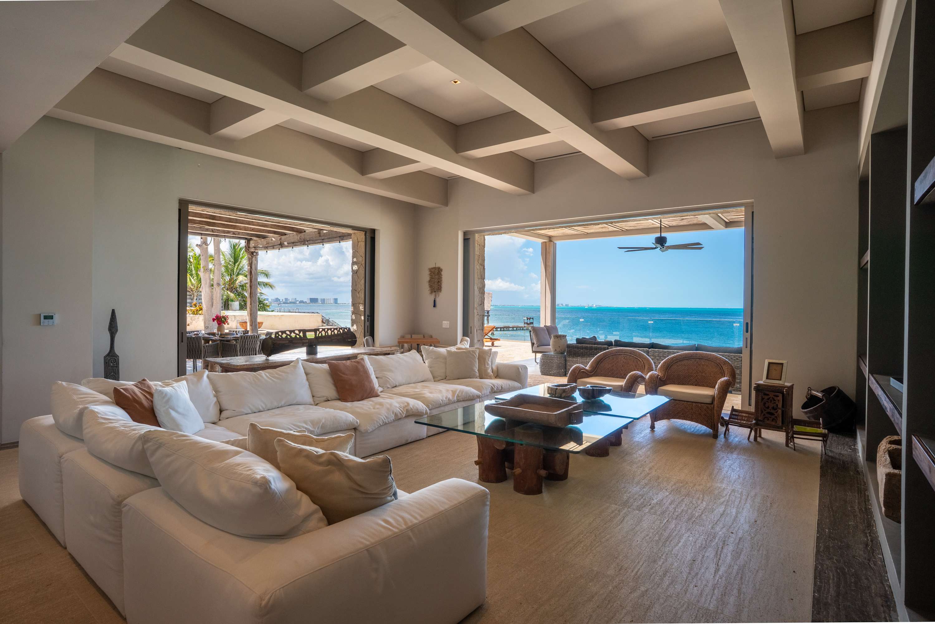 A large white sectional sofa faces a glass coffee table in a living room with ocean views.