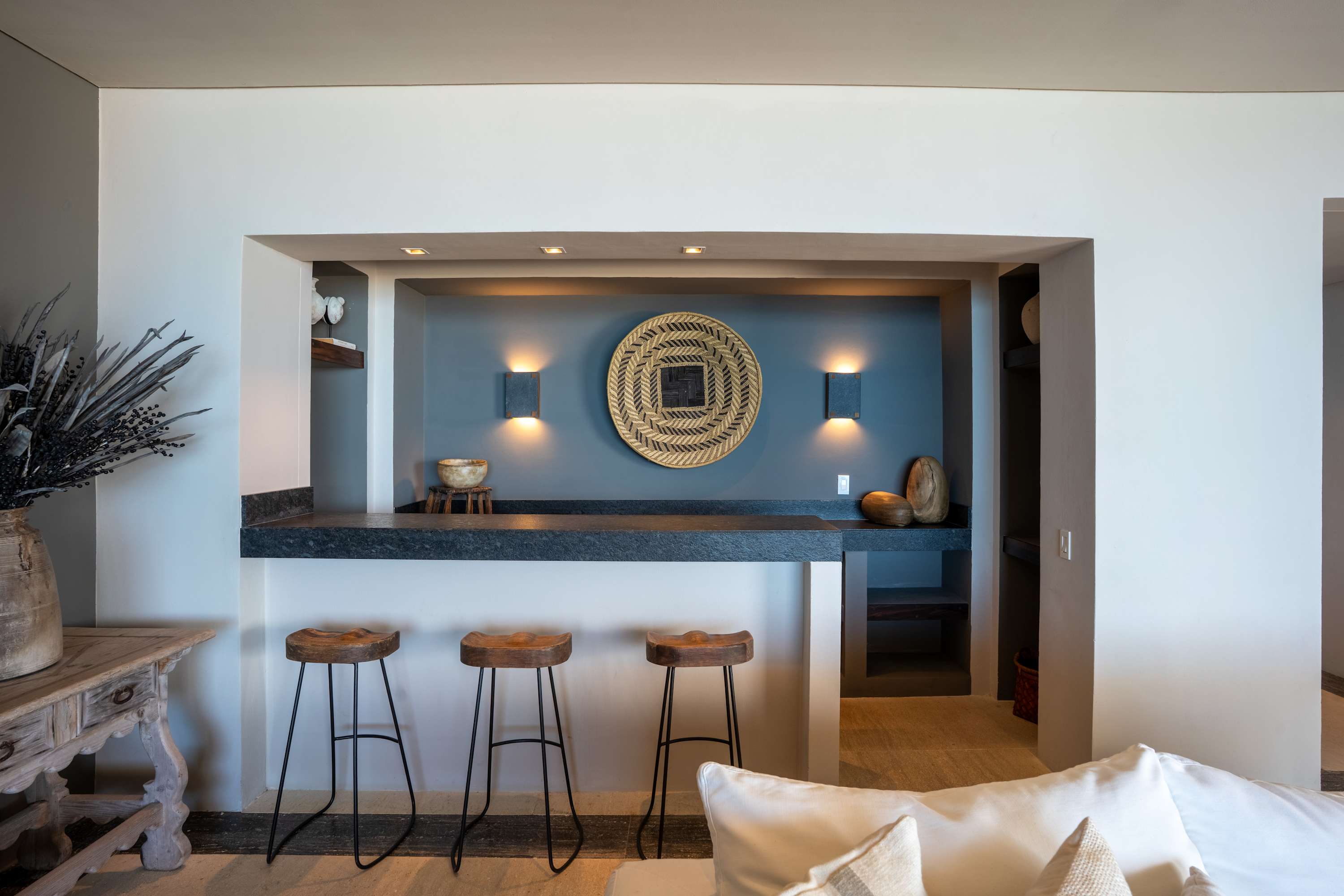 Interior view of a modern home bar with three stools.