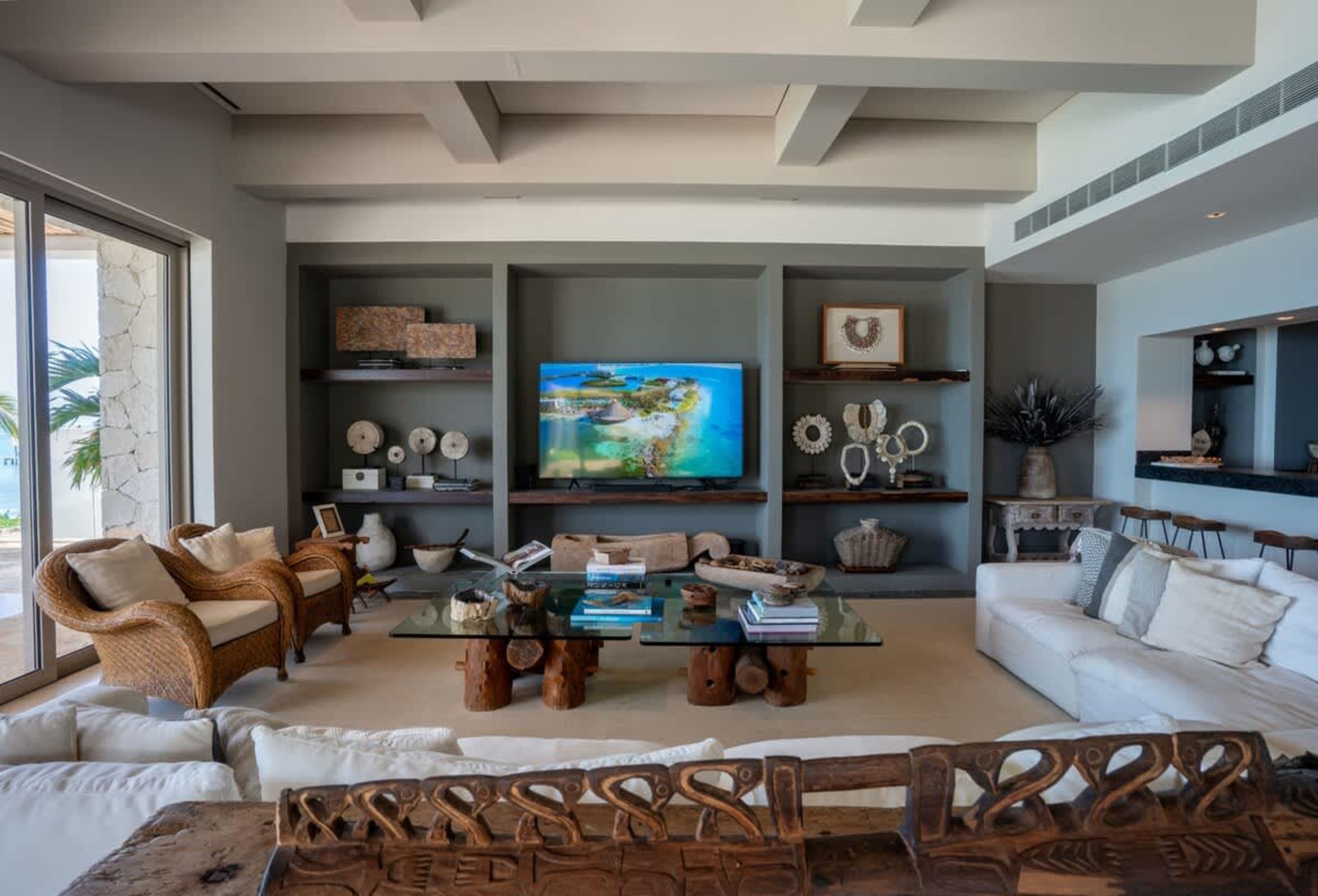 A living room with wicker chairs, a glass coffee table, and a TV.