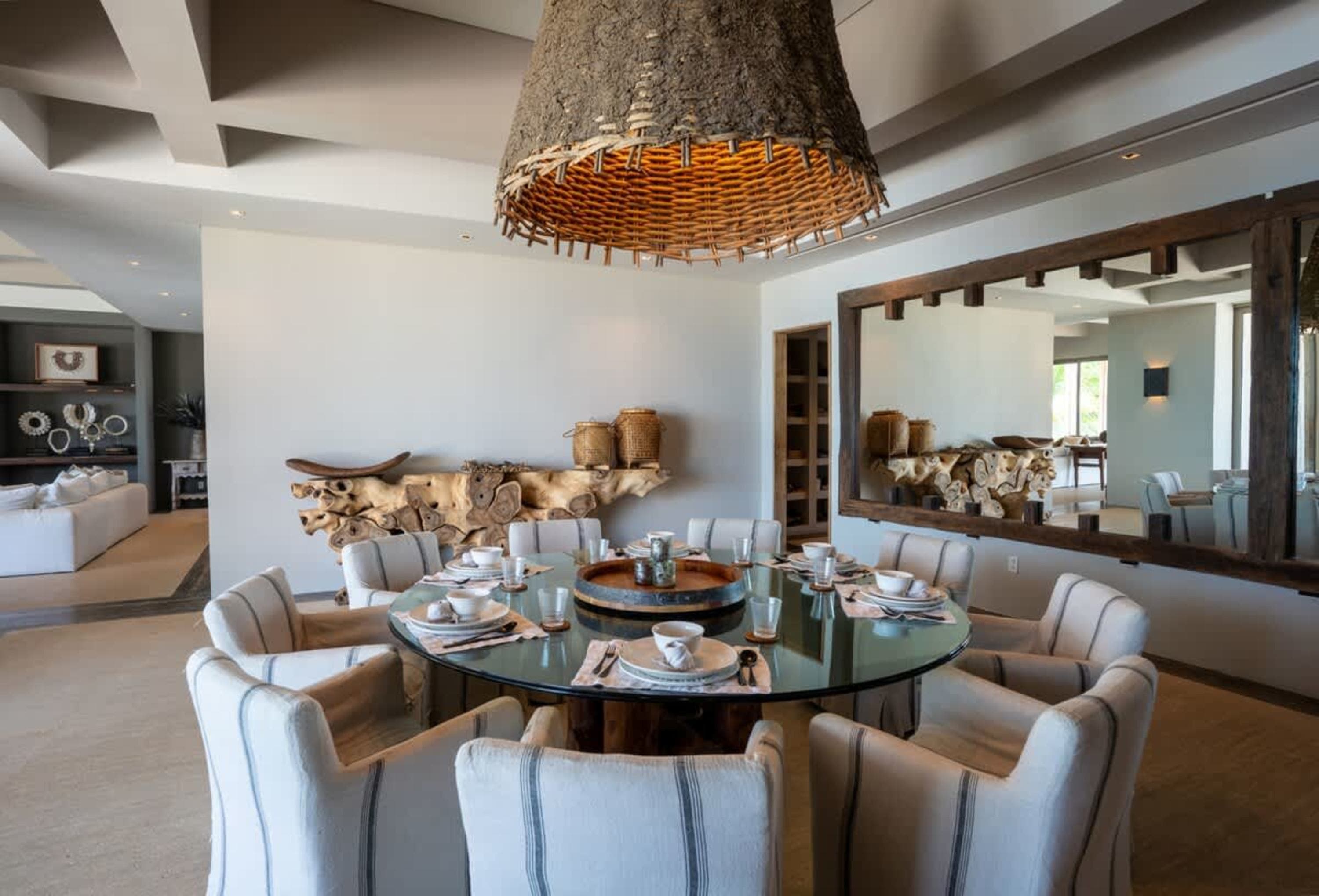 A rustic dining room with a large round glass table and chairs.