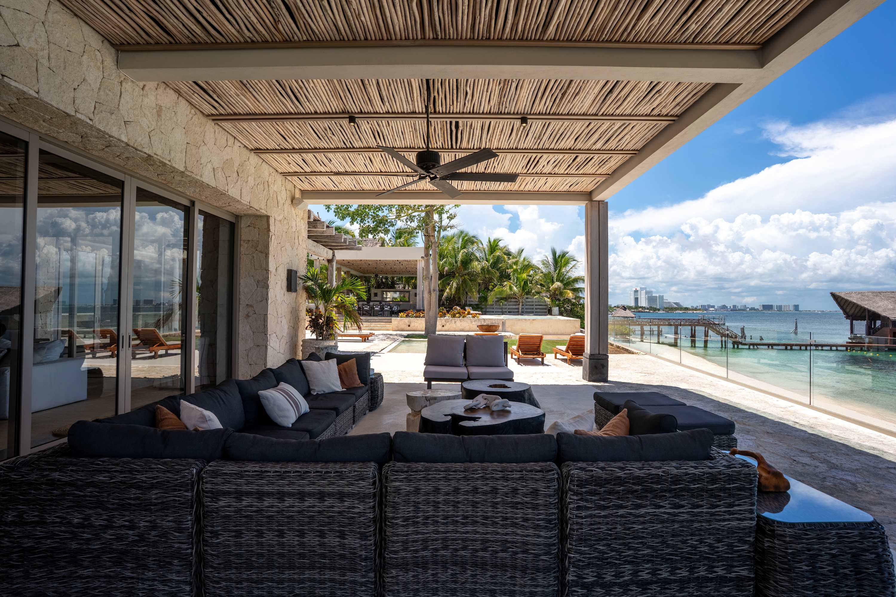 Spacious patio with wicker furniture, ceiling fan, and ocean view.