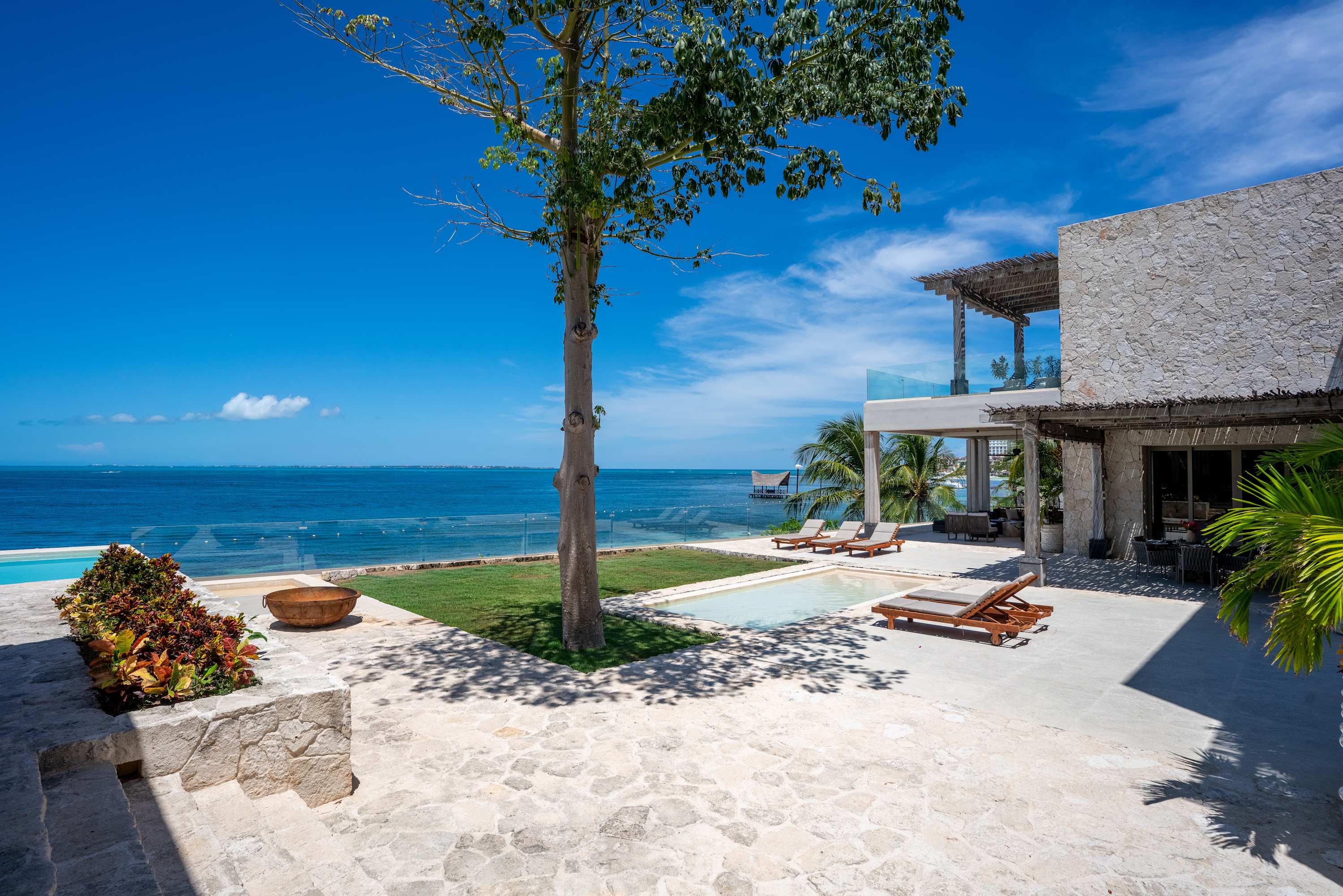 A tropical villa with a pool, lounge chairs, and ocean view.