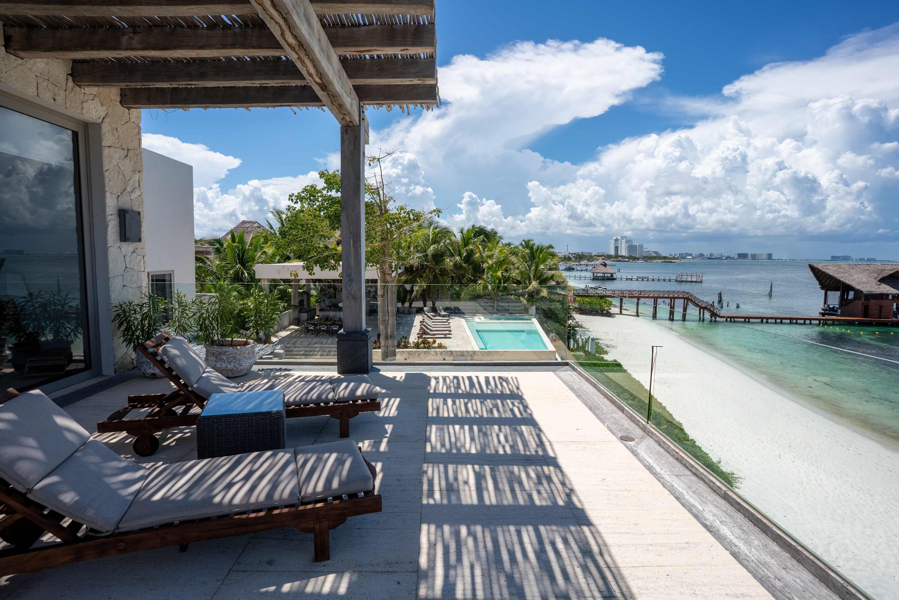 Luxury resort balcony overlooking the ocean, beach, and infinity pool.