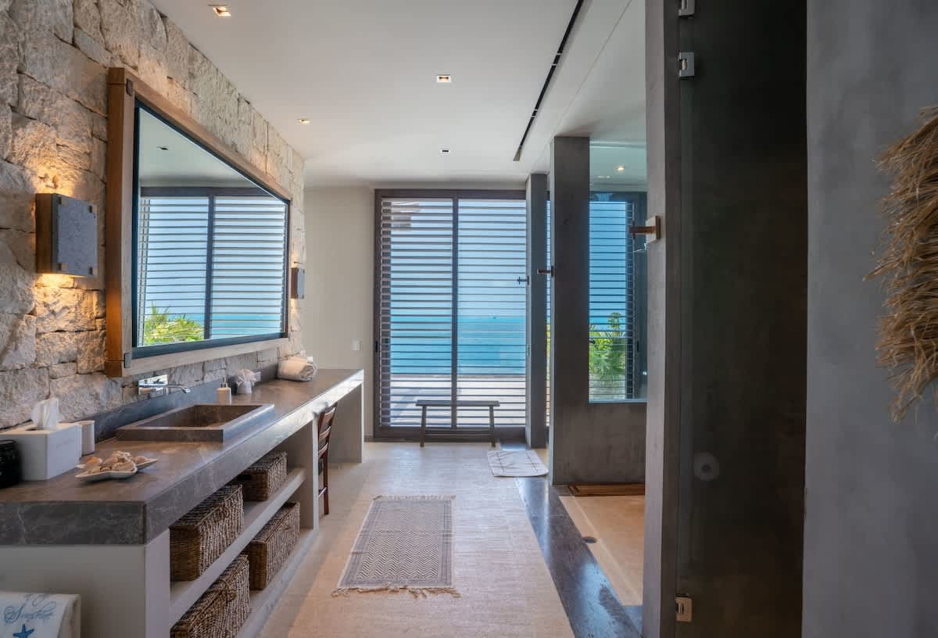 A modern bathroom with a double sink, large mirror, and ocean view.