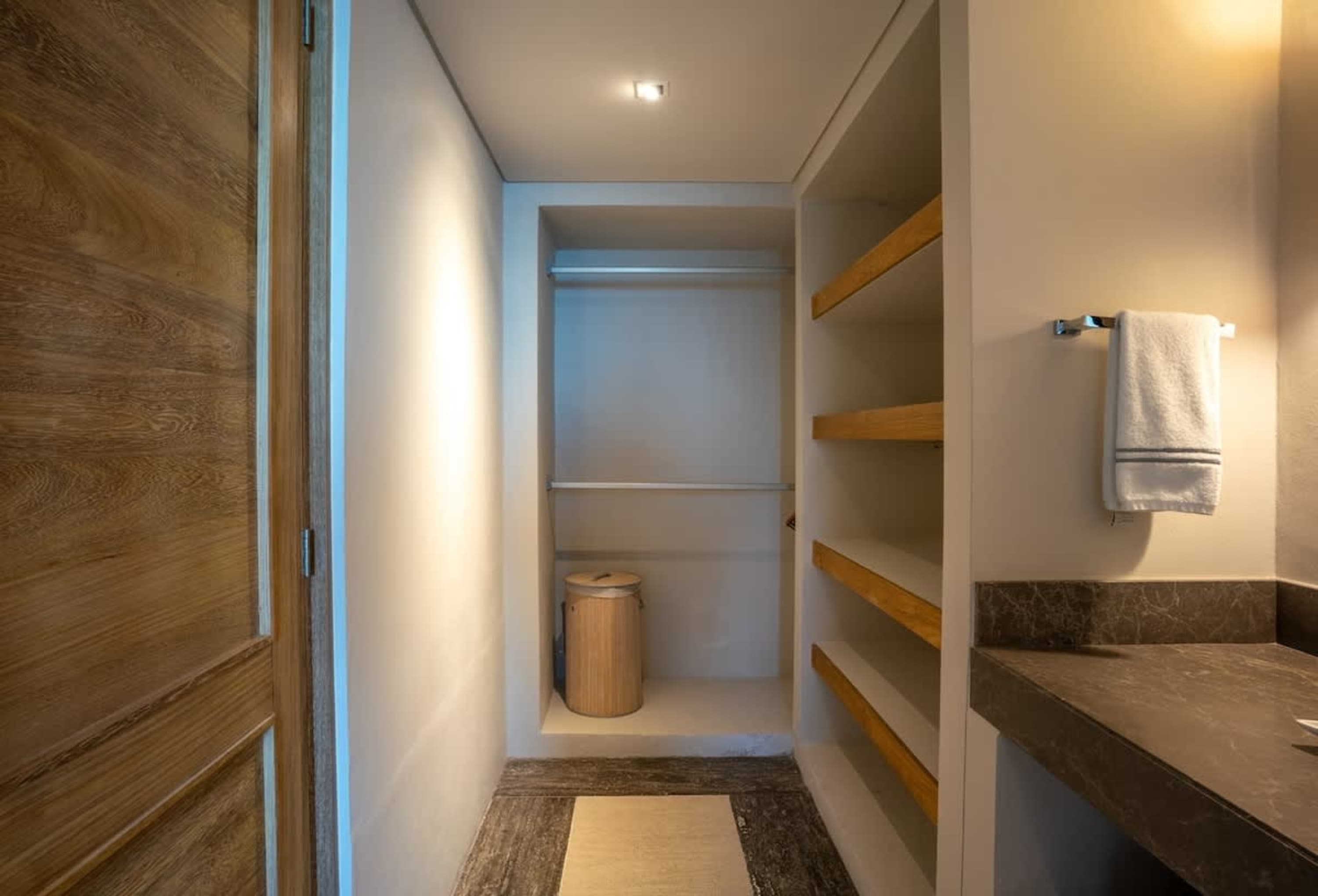 A minimalist closet with wooden shelves and a door next to it.