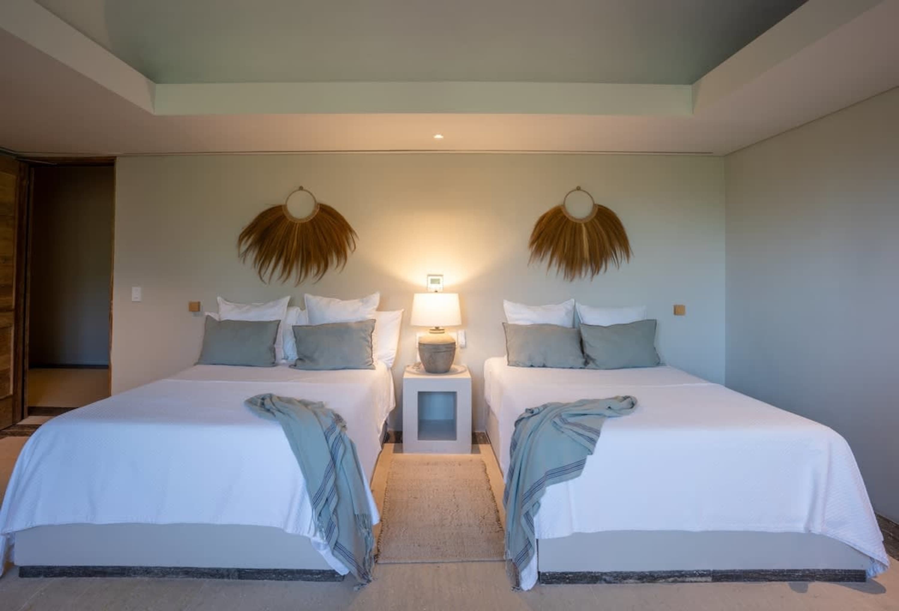 Two beds with white bedding and light blue throws are in a room.