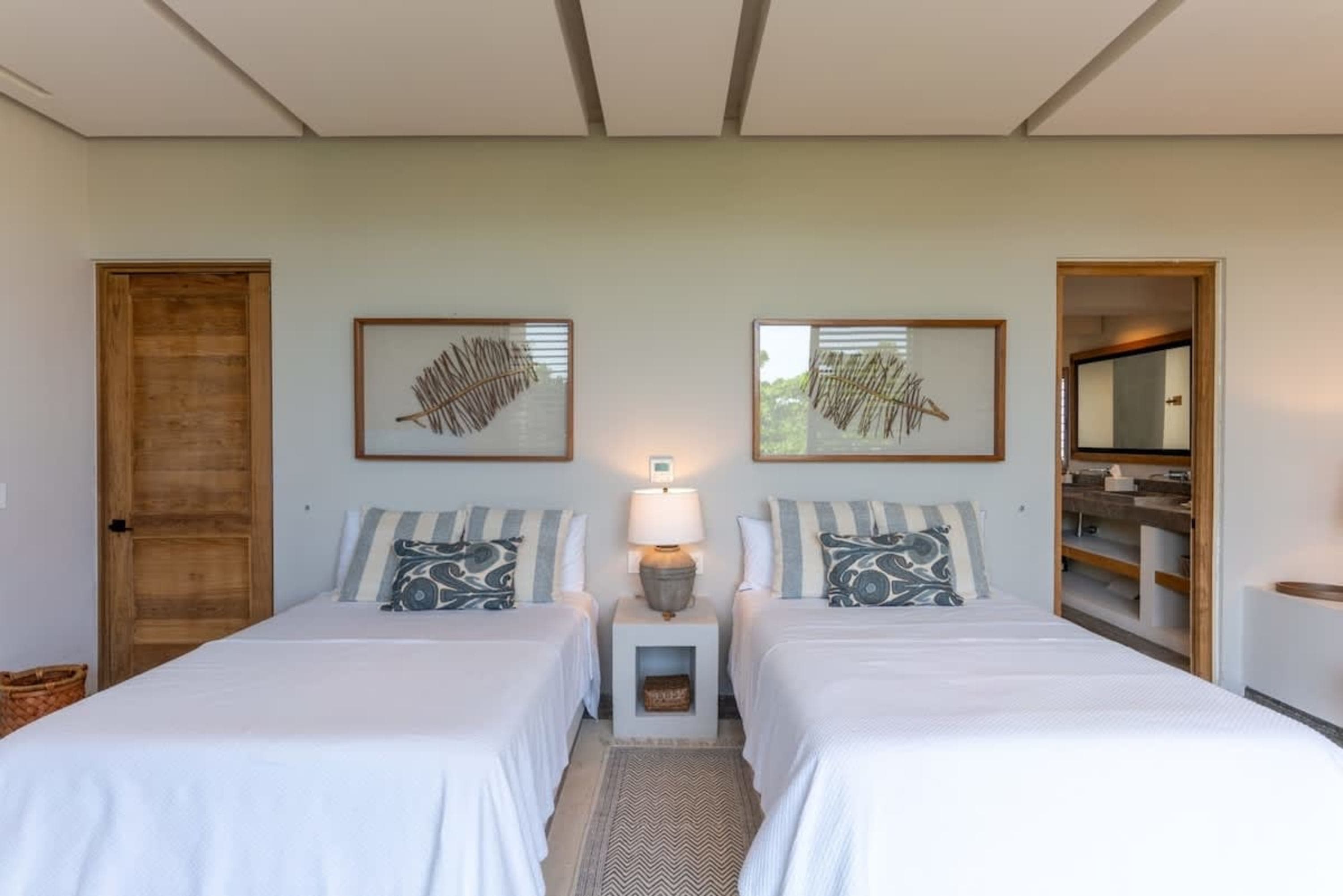 A bedroom with two twin beds, each with white bedding and striped pillows.