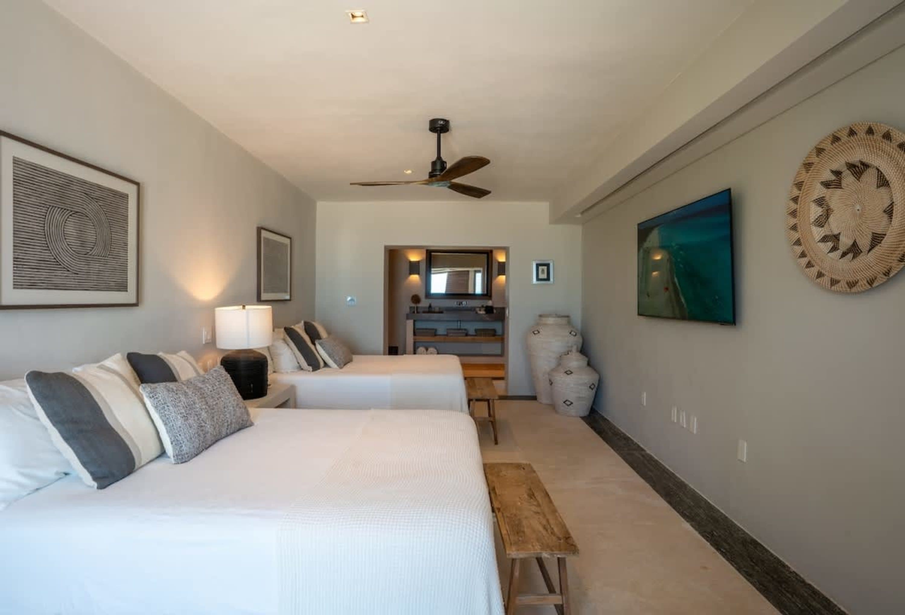 A bedroom with two beds, a TV, and decorative vases.