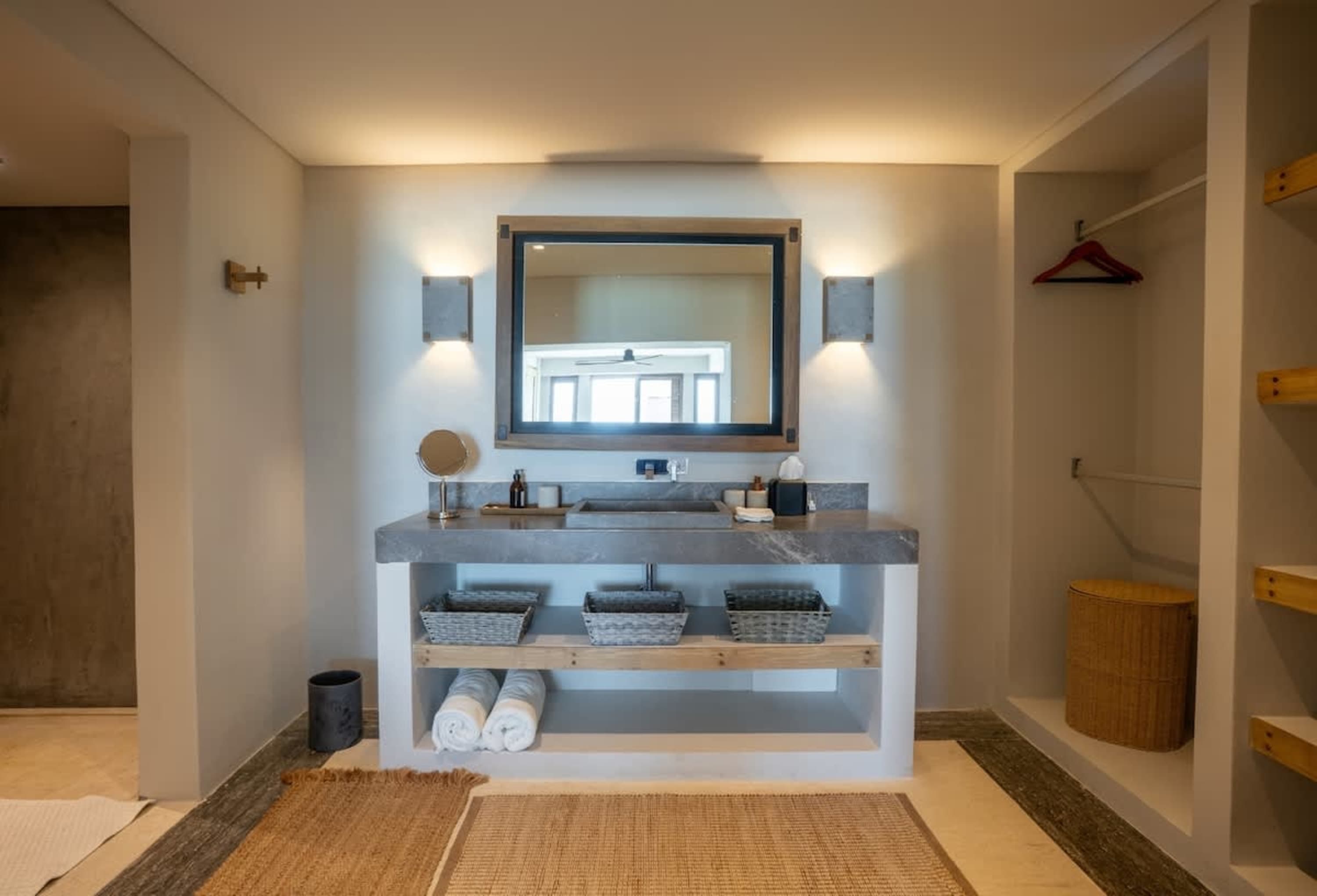 A modern bathroom vanity with a large mirror and integrated sink, flanked by lights.