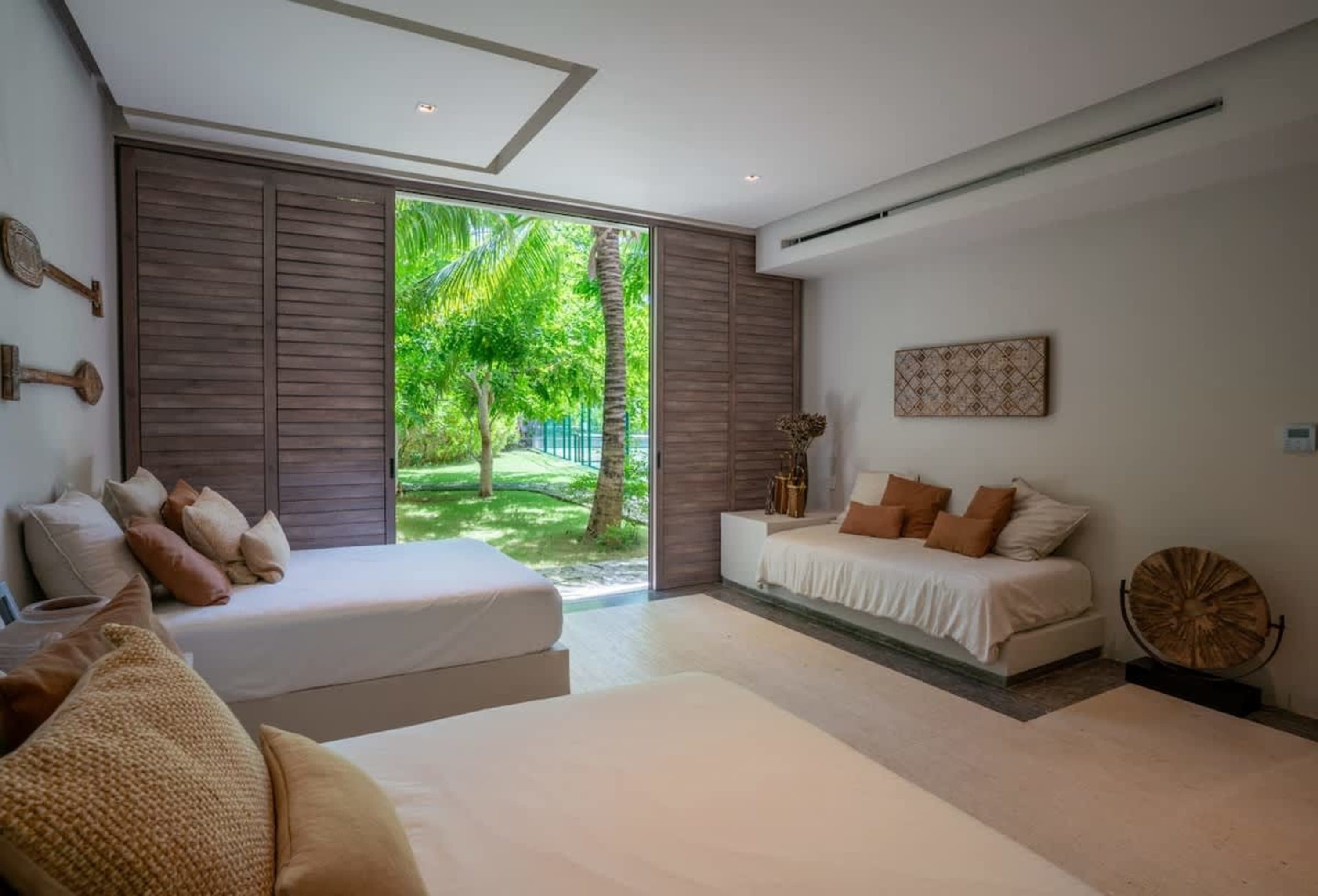 Two beds in a room with sliding glass doors to a green outdoor space.