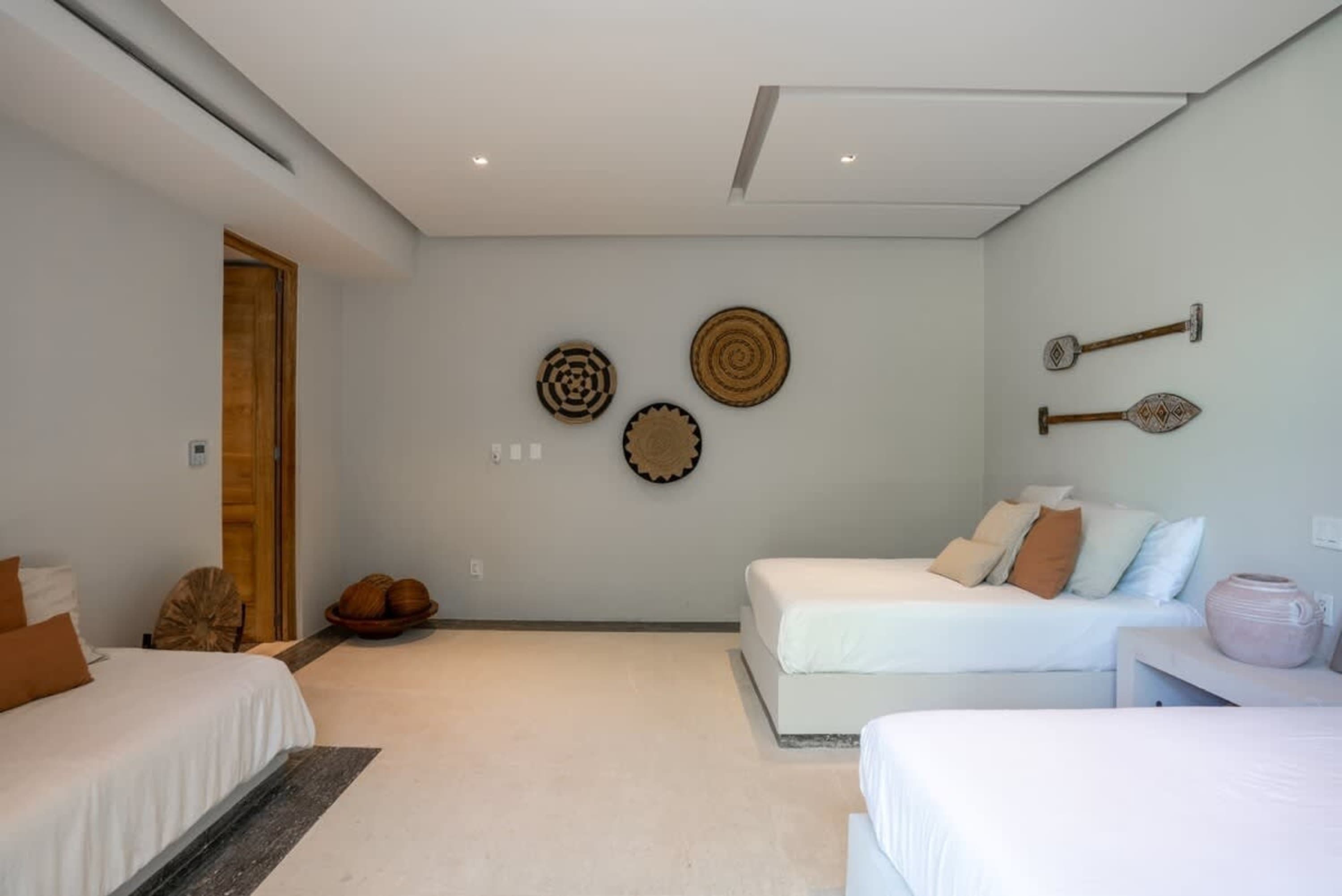 A bedroom with two white beds, decorative wall art, and natural wood accents.