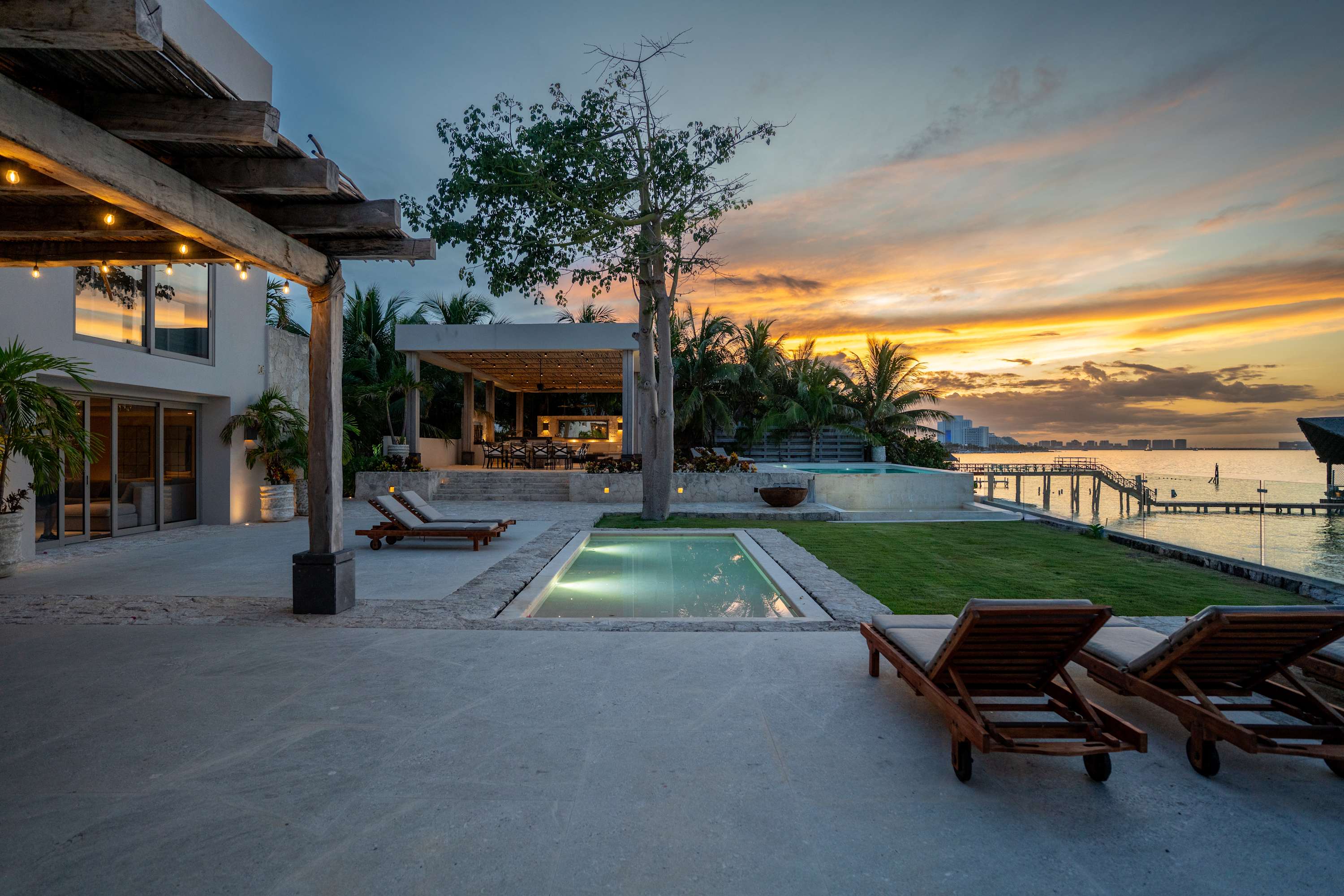 A luxurious villa with a pool and ocean view at sunset.