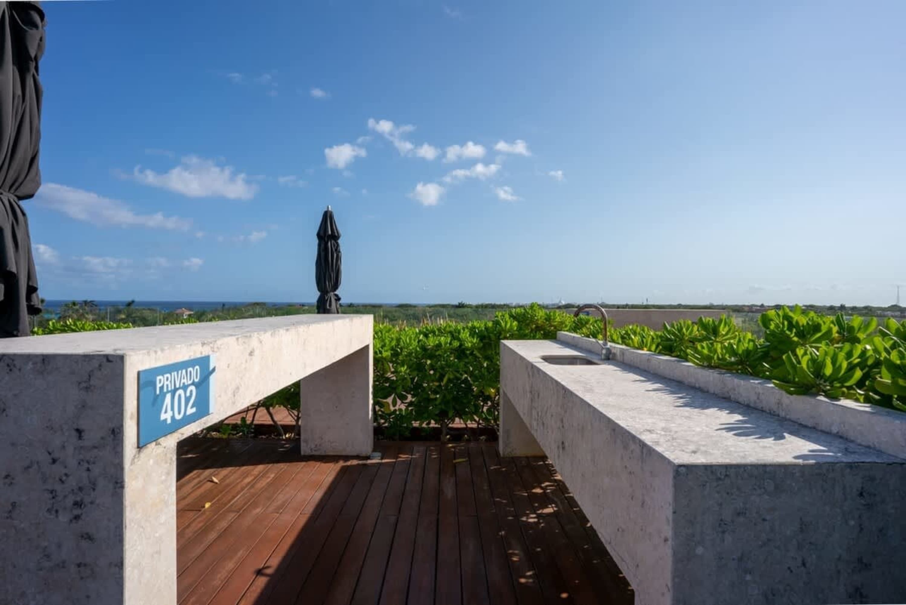 Rooftop outdoor kitchen with concrete counters, a sink, and a view of the ocean.