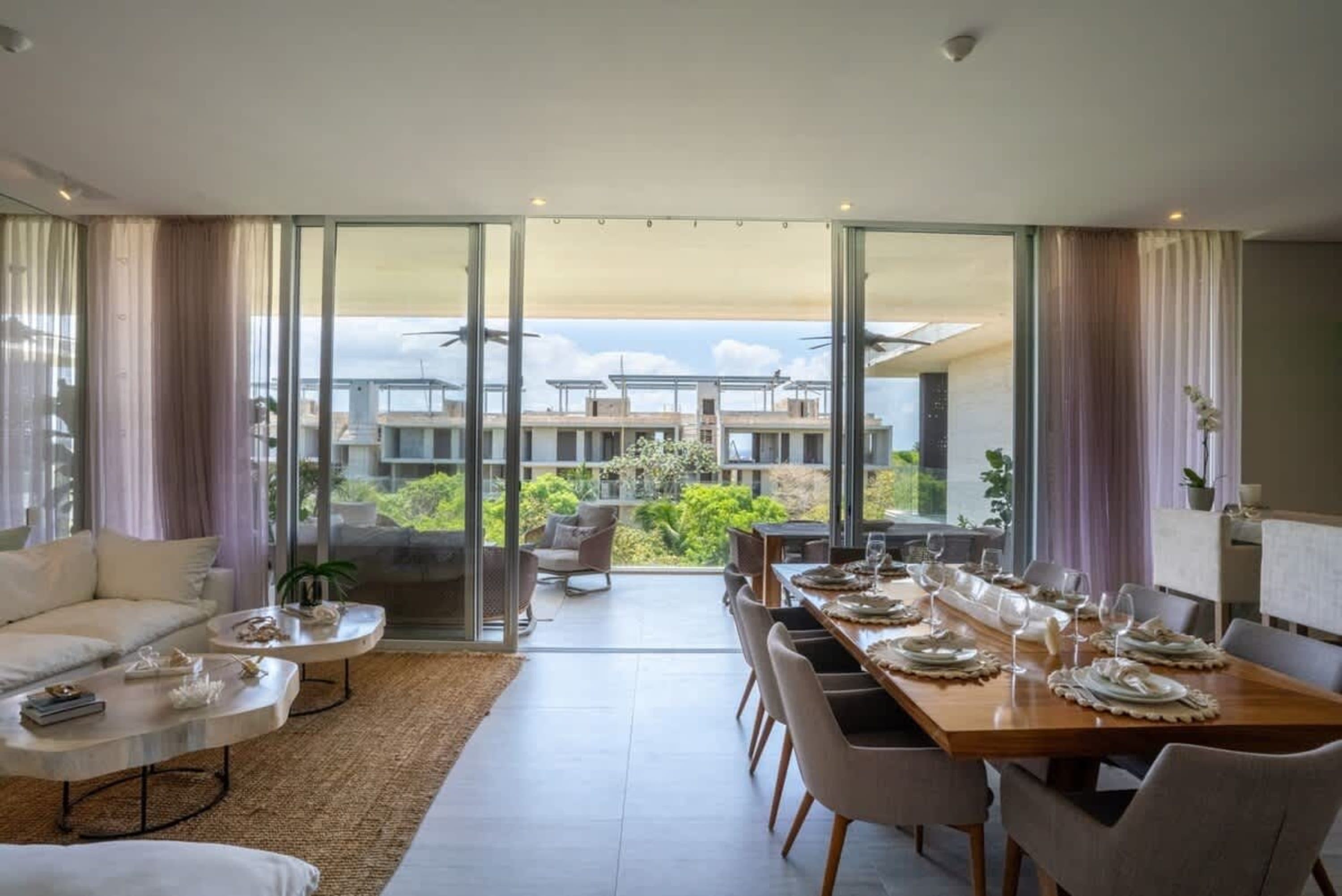 Dining room with a long table set for a meal and a living room with a sectional couch.